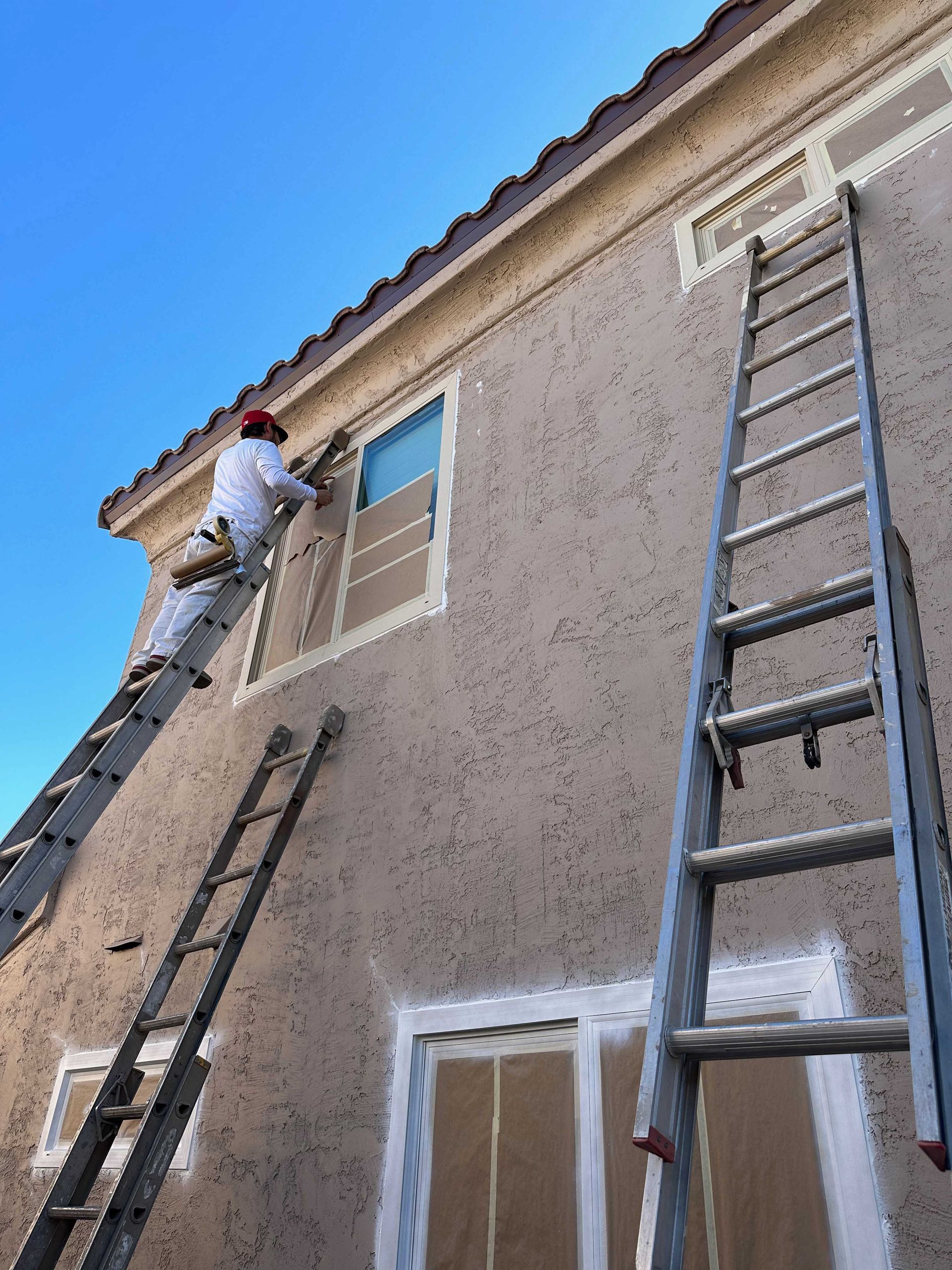 A man on a ladder paints the side of a building