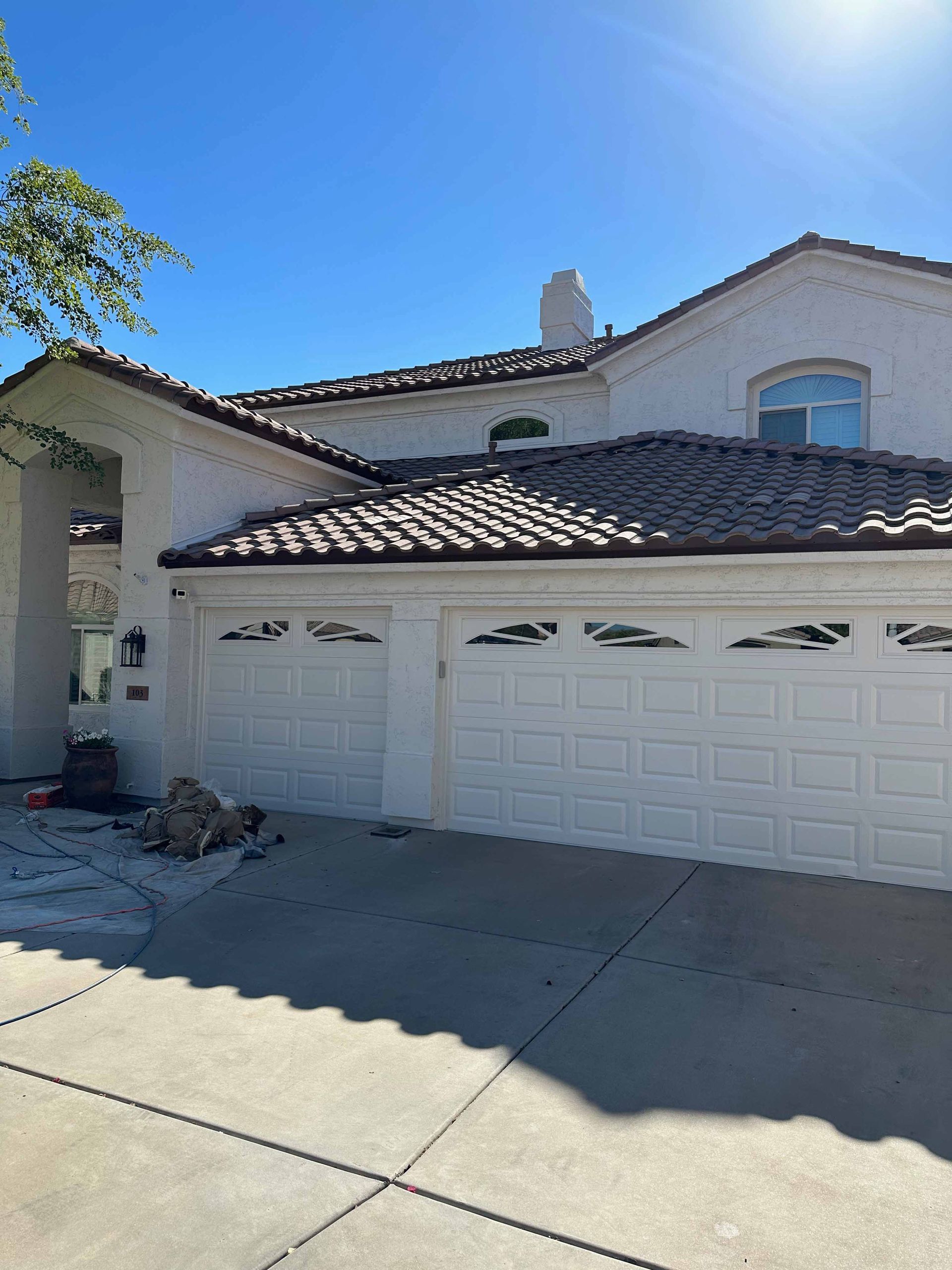 A white house with two garage doors and a tile roof.