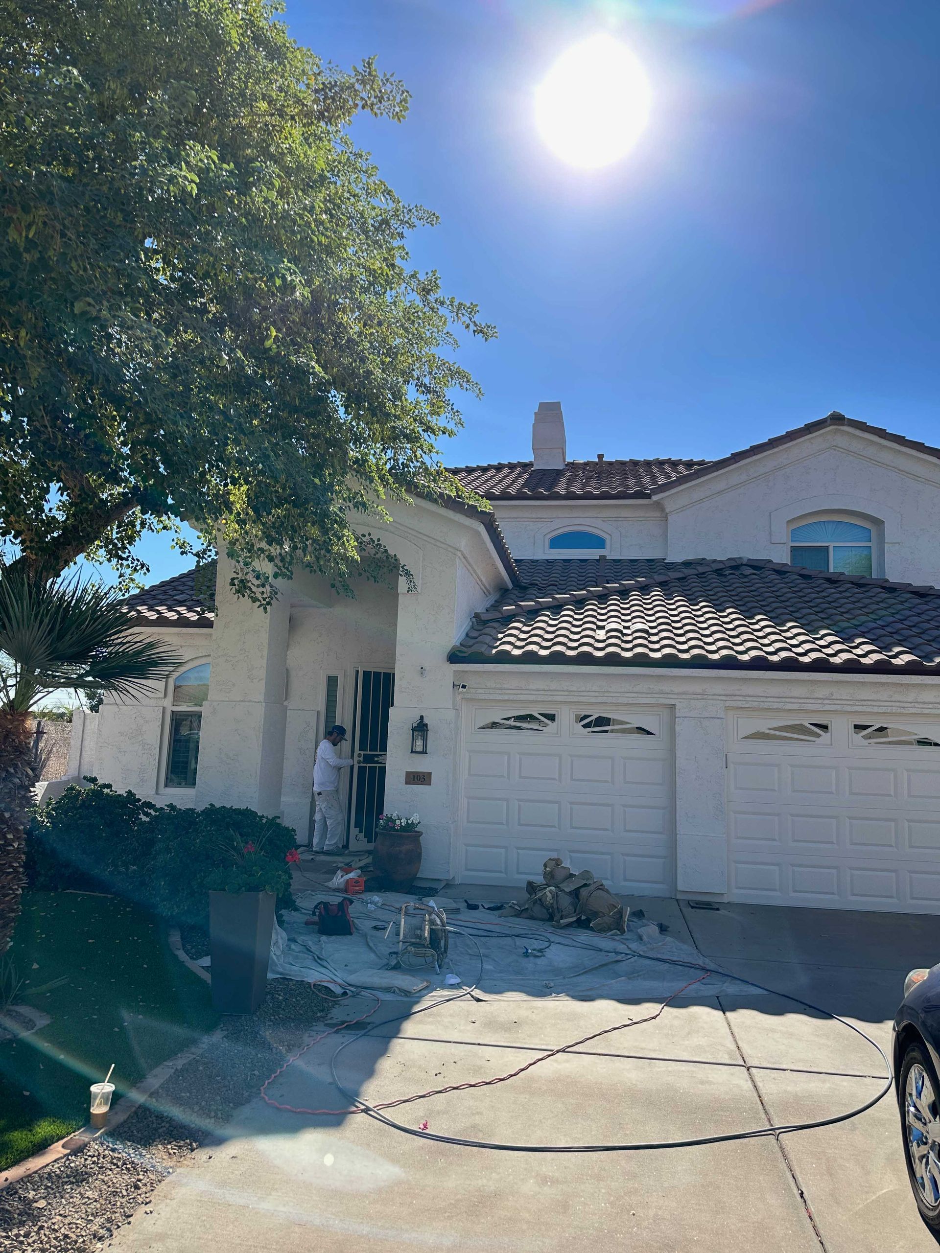 A white house with a car parked in front of it on a sunny day.