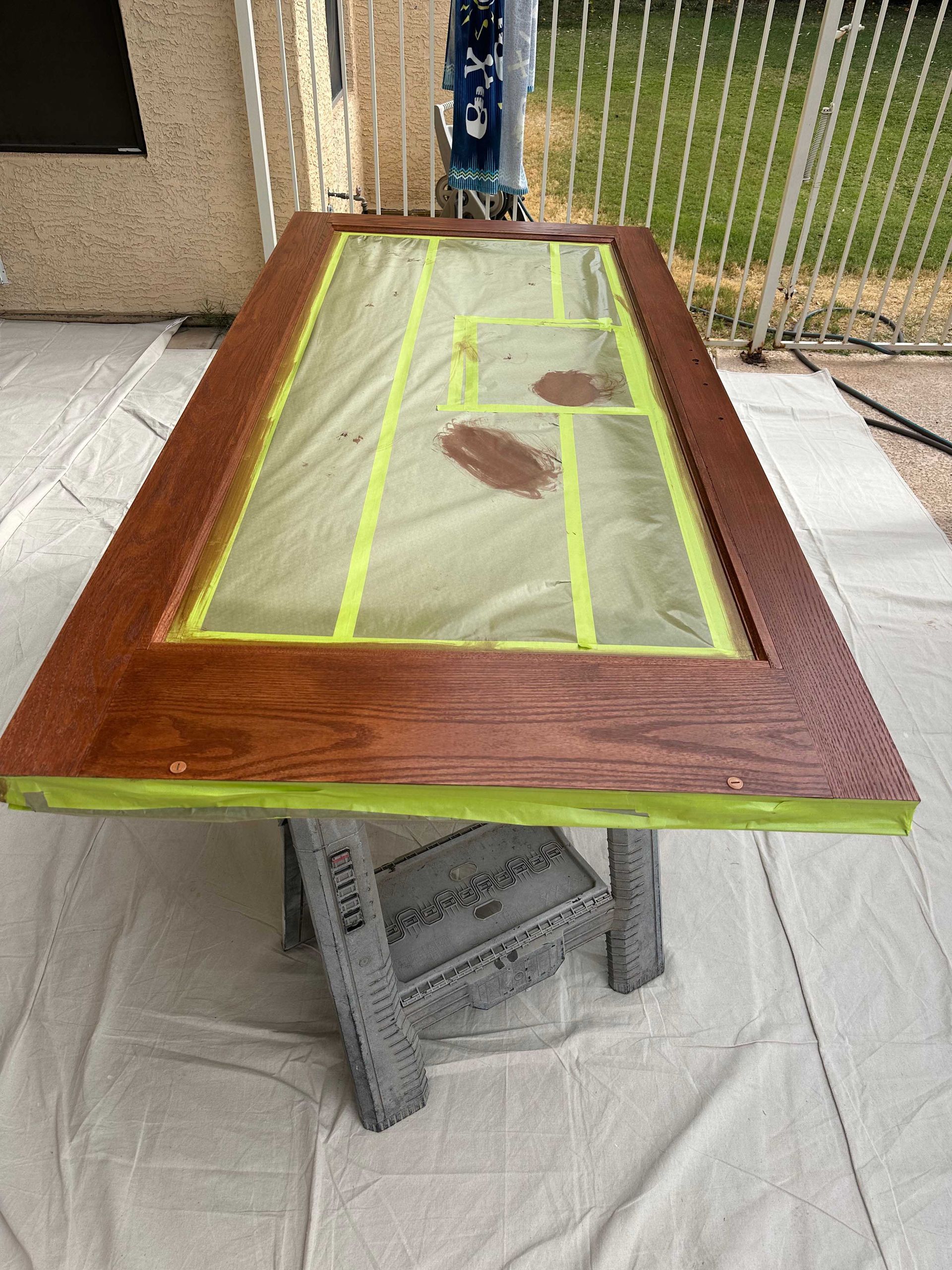 A wooden door is sitting on top of a table with tape on it.