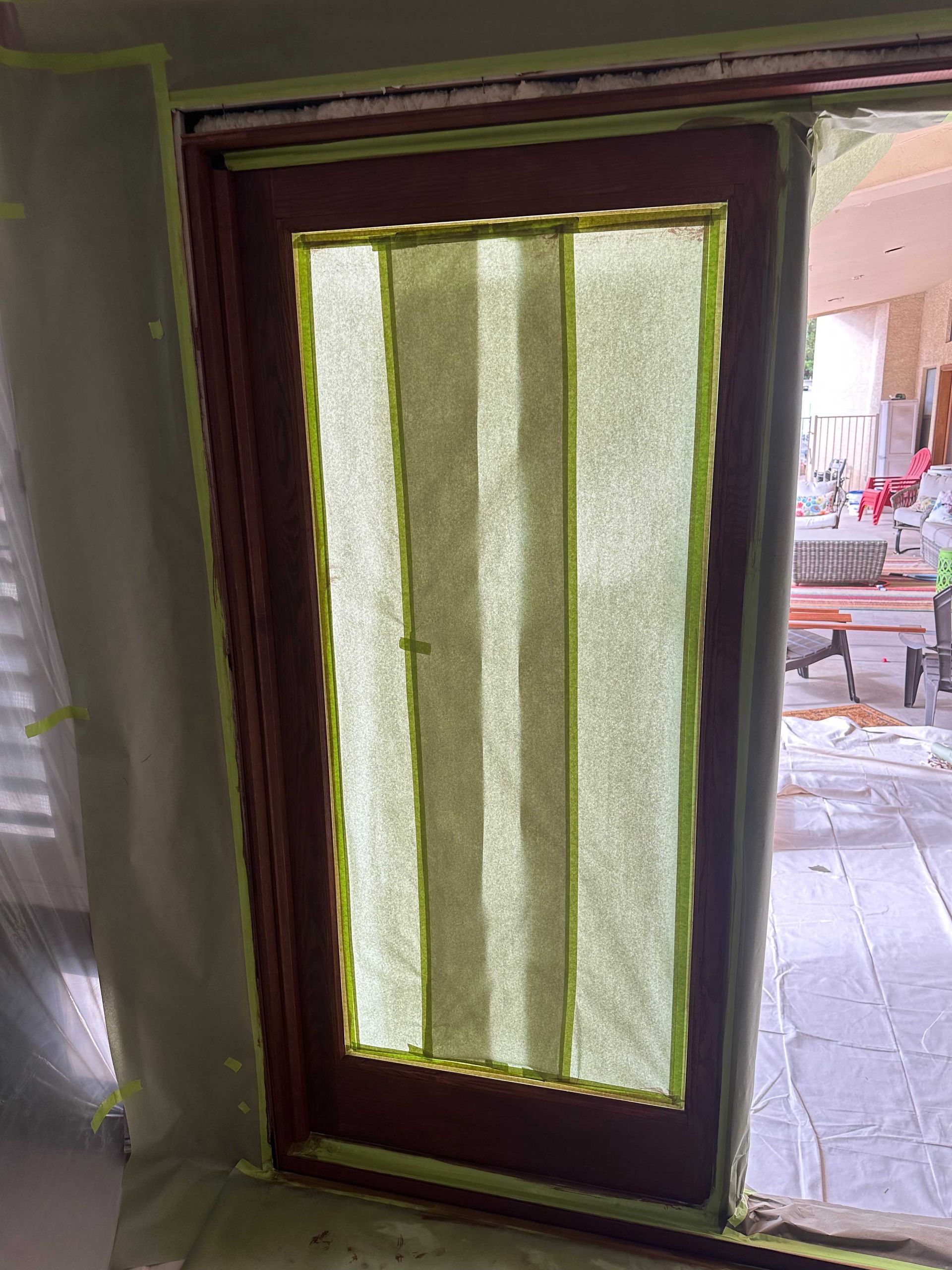 A door is being painted in a room with green tape.