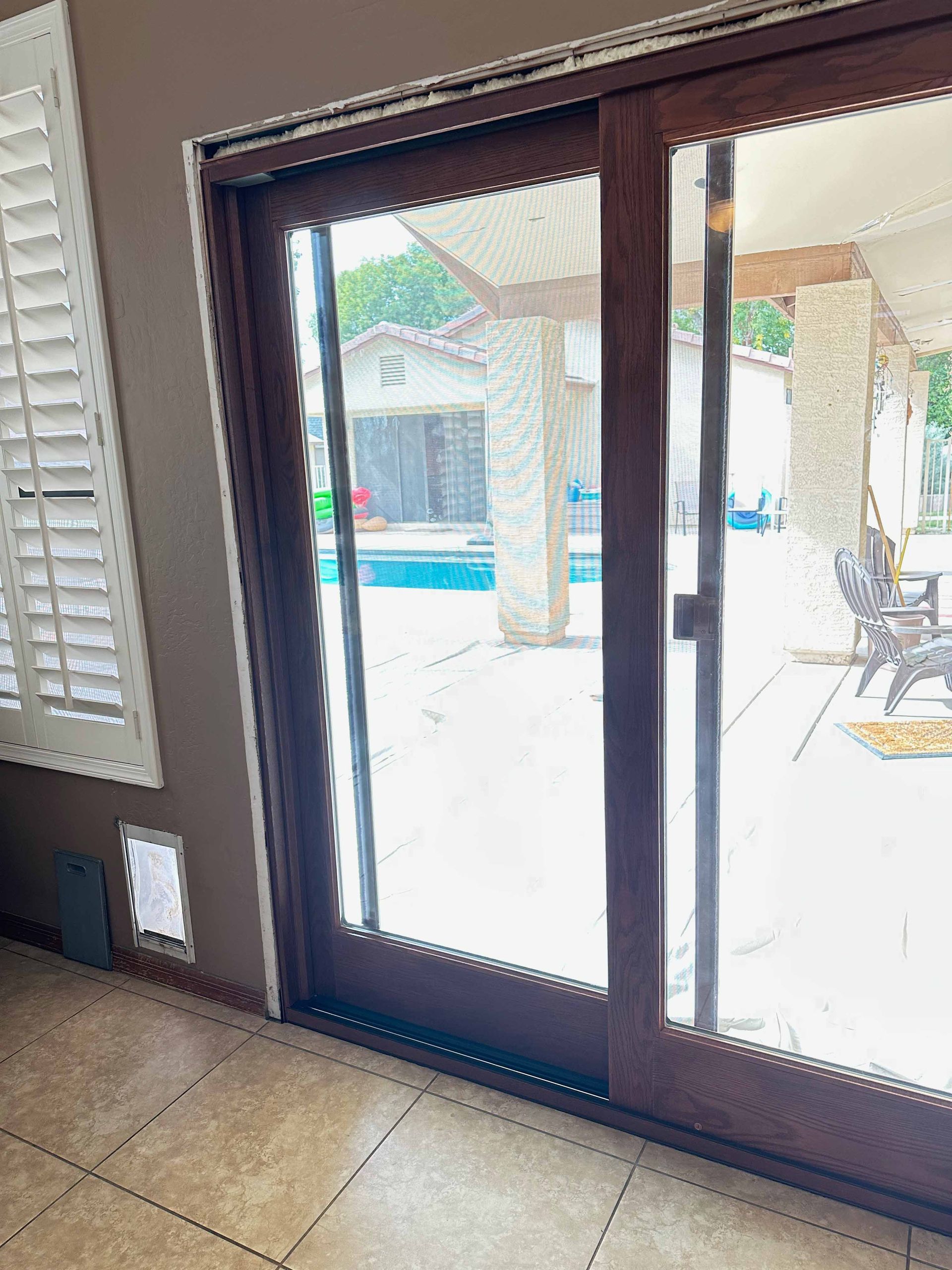 A sliding glass door leading to a patio with a pool in the background.