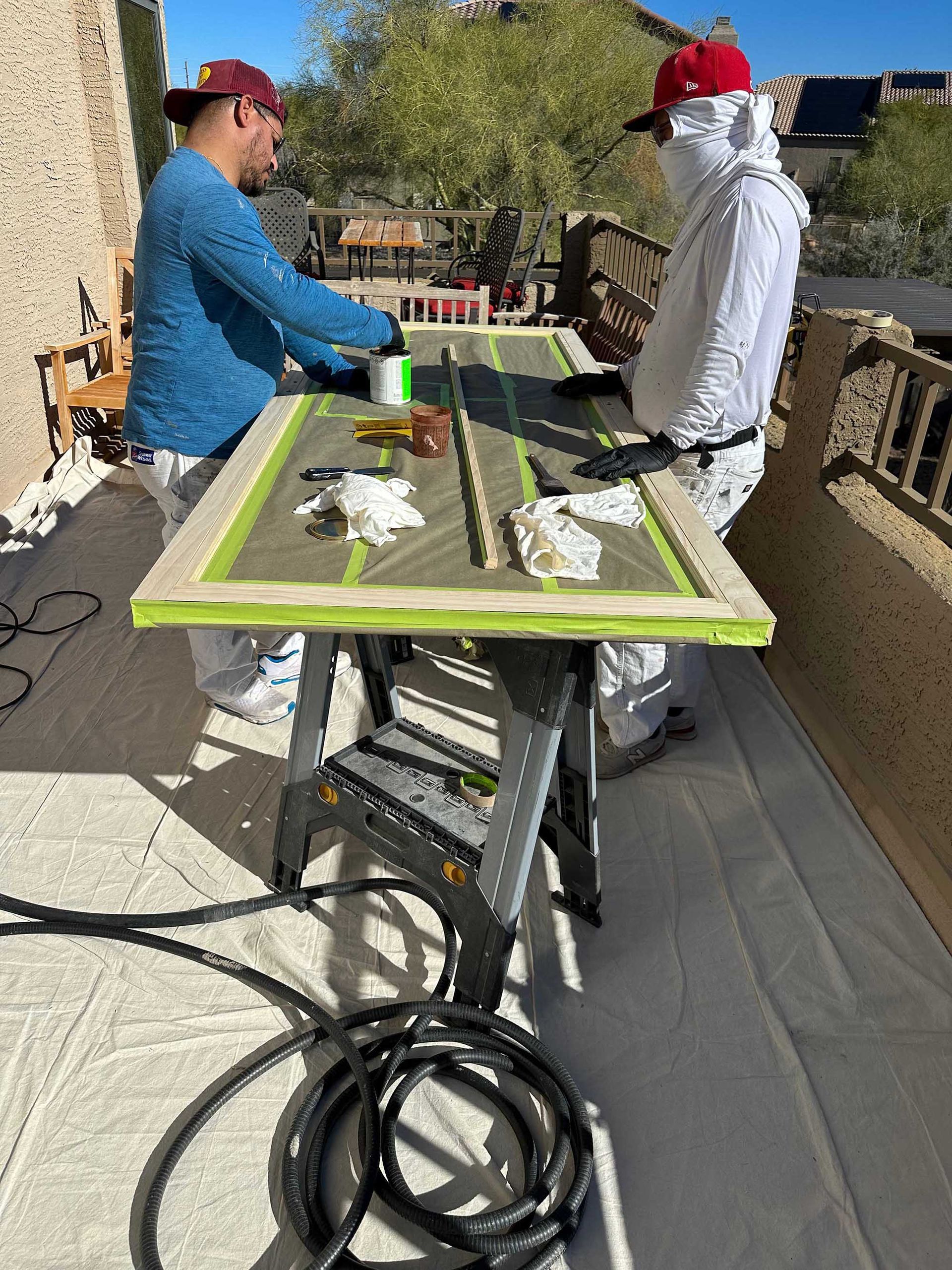 Two men are working on a table on a balcony.