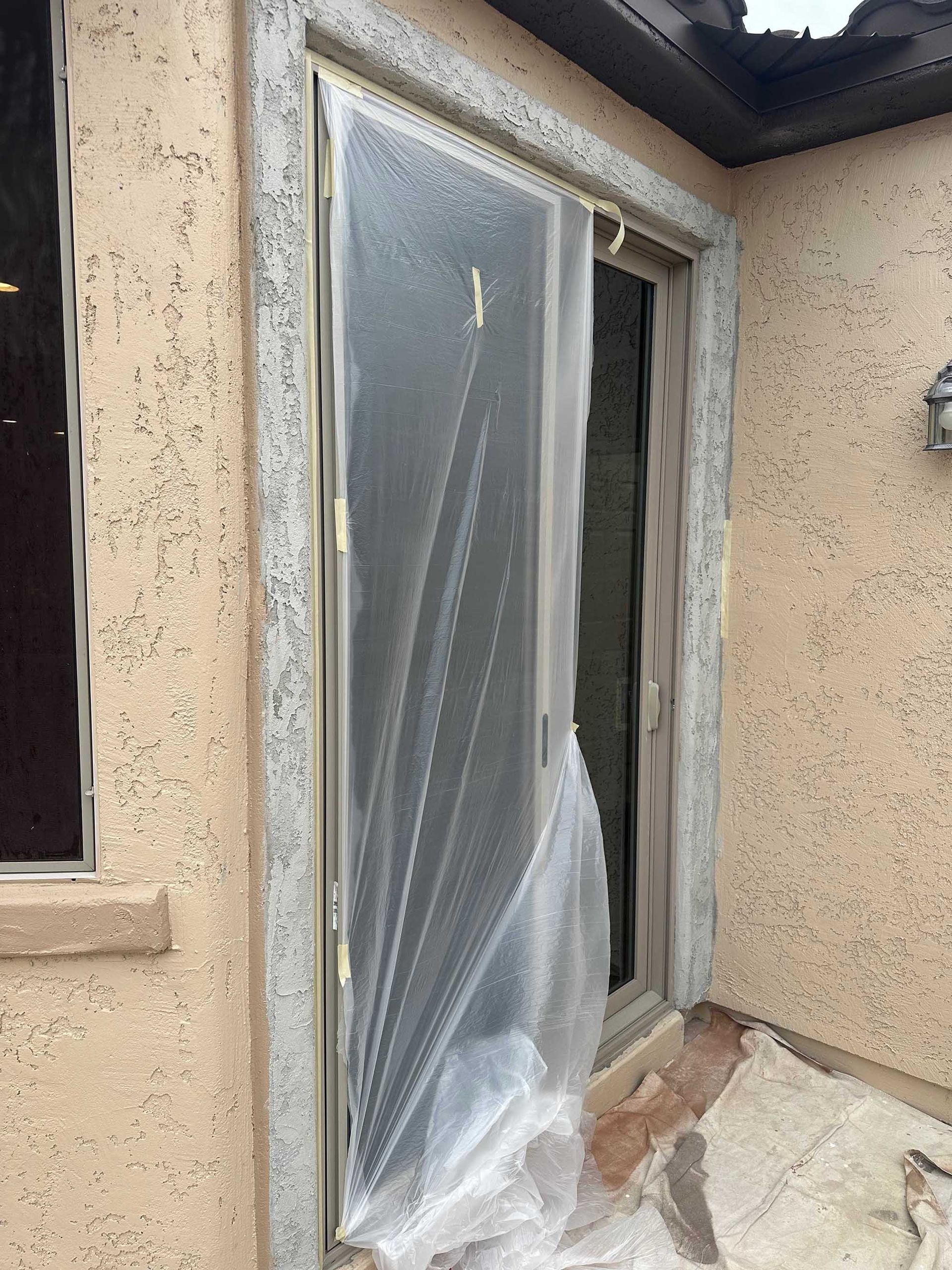 A sliding glass door is covered in plastic.