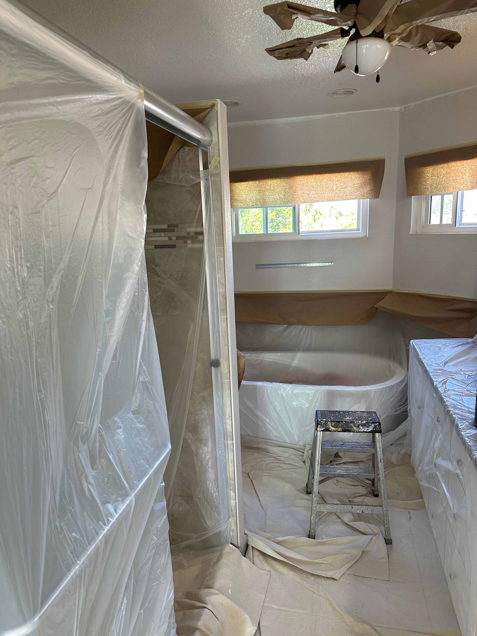 A bathroom with a bathtub and a ladder covered in plastic.