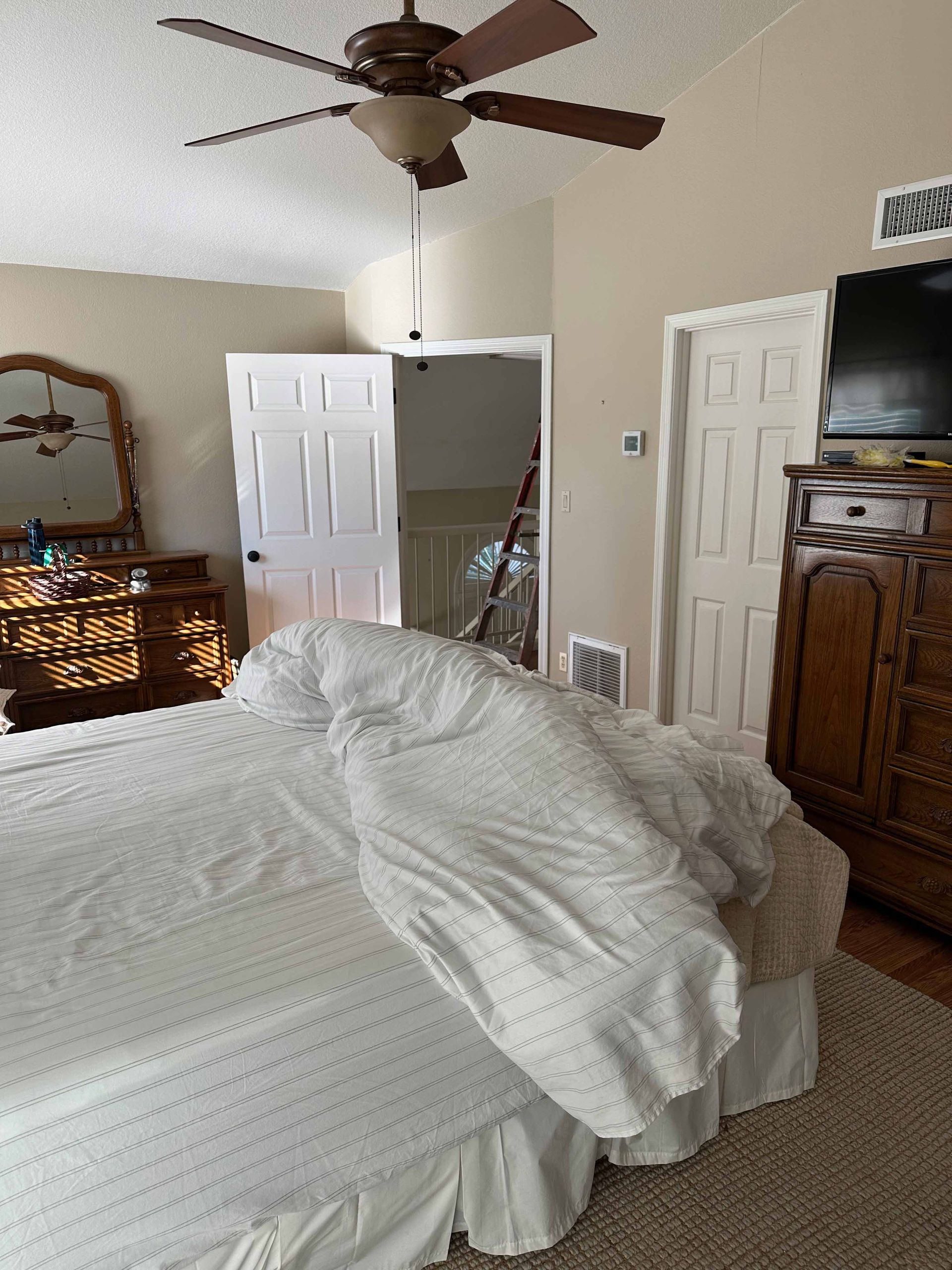 A bedroom with a bed , dresser , mirror and ceiling fan.