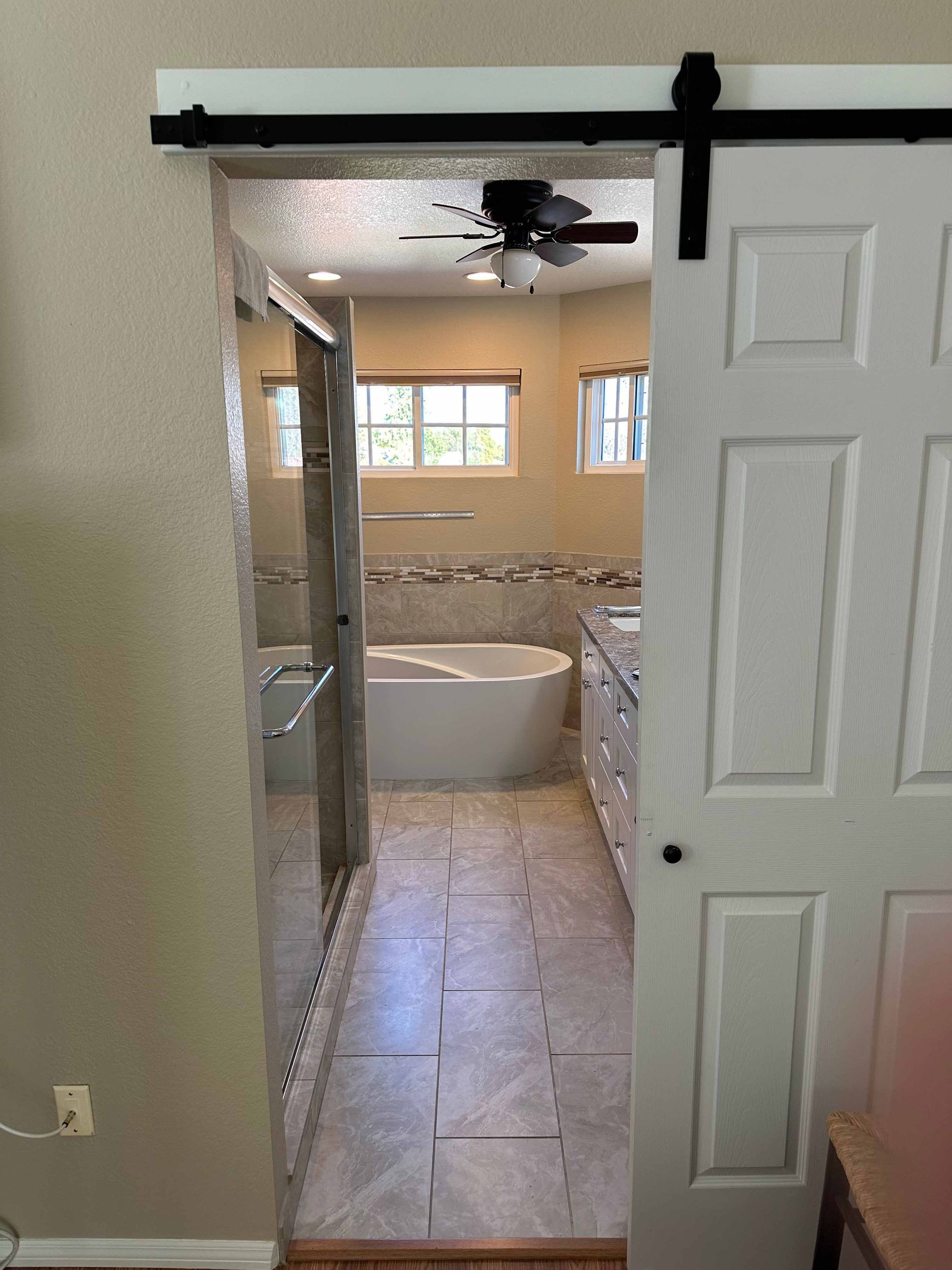 A bathroom with a sliding barn door leading to it.