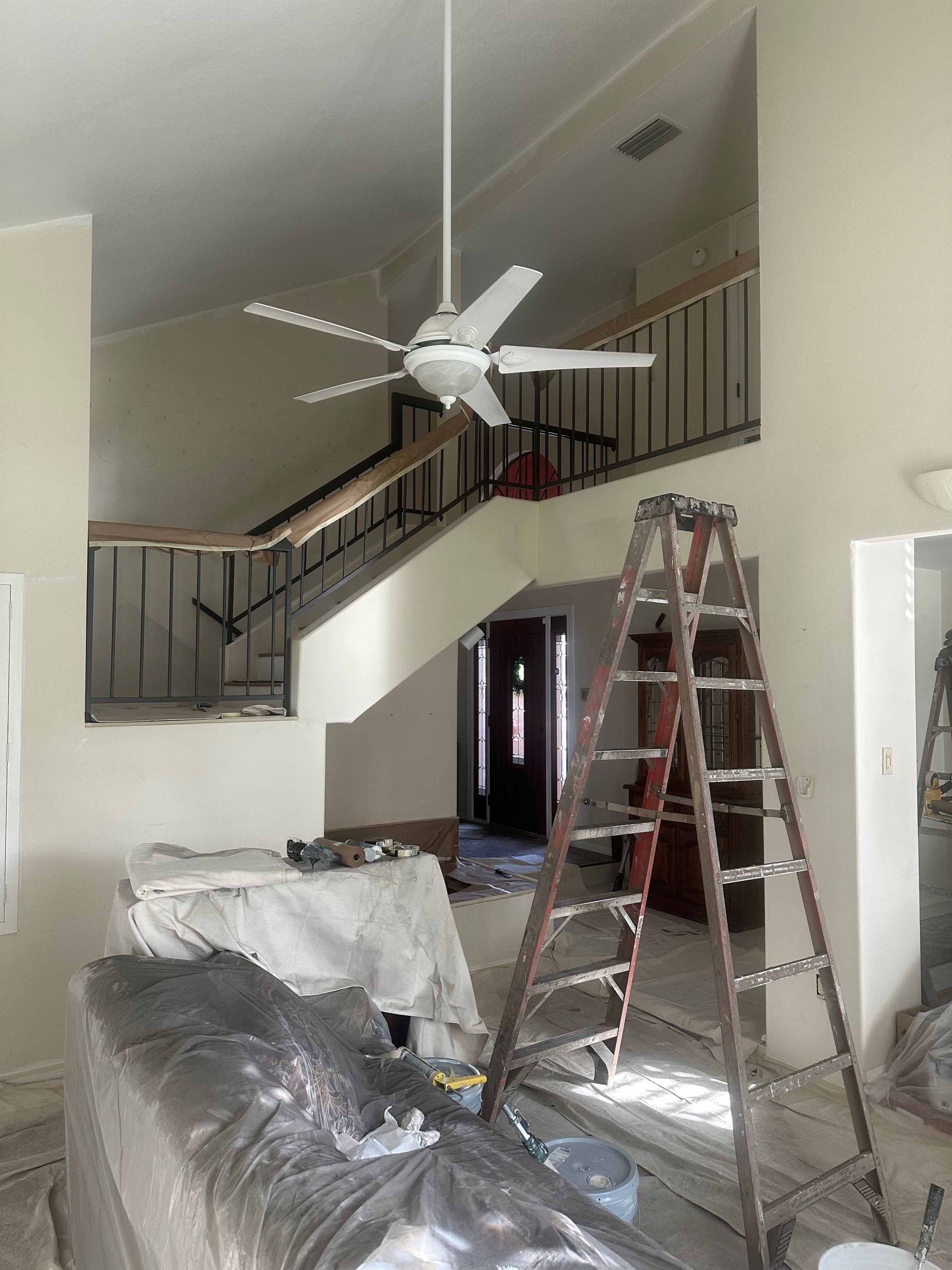 A ceiling fan is hanging from the ceiling in a room with a ladder.