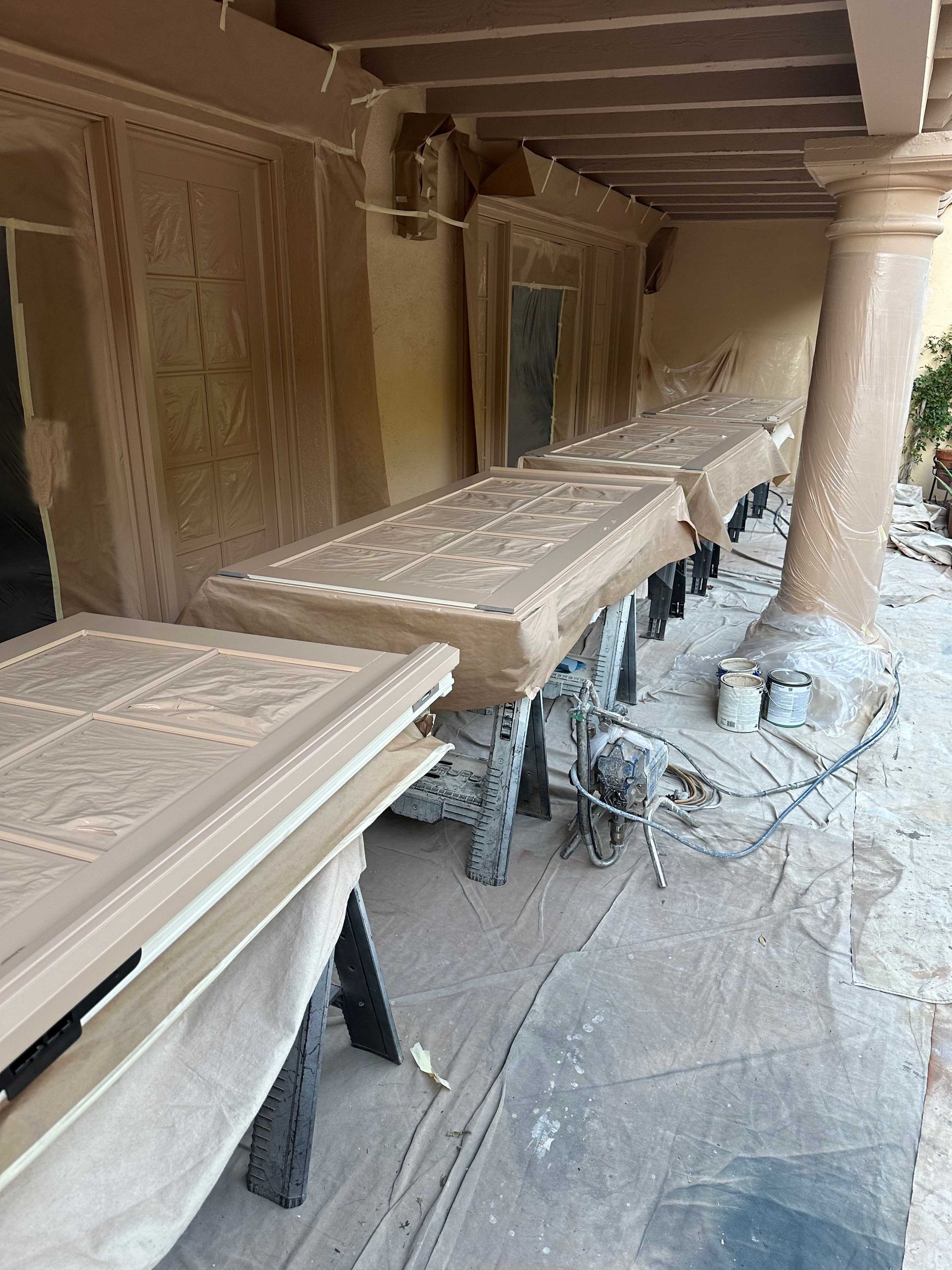 A row of wooden tables are sitting under a covered porch.