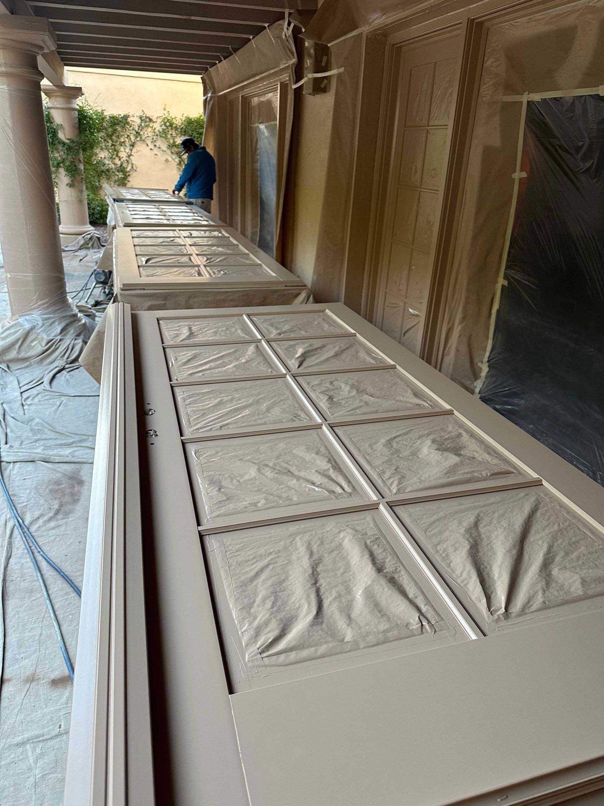 A man is standing behind a row of doors that are being painted