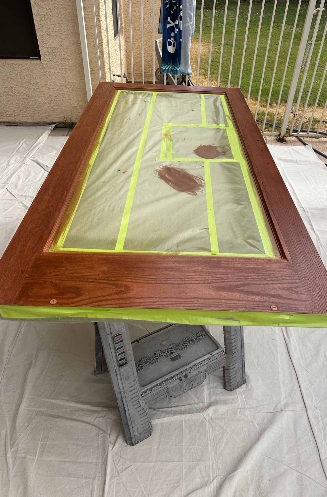 A wooden door is sitting on top of a table with tape on it.
