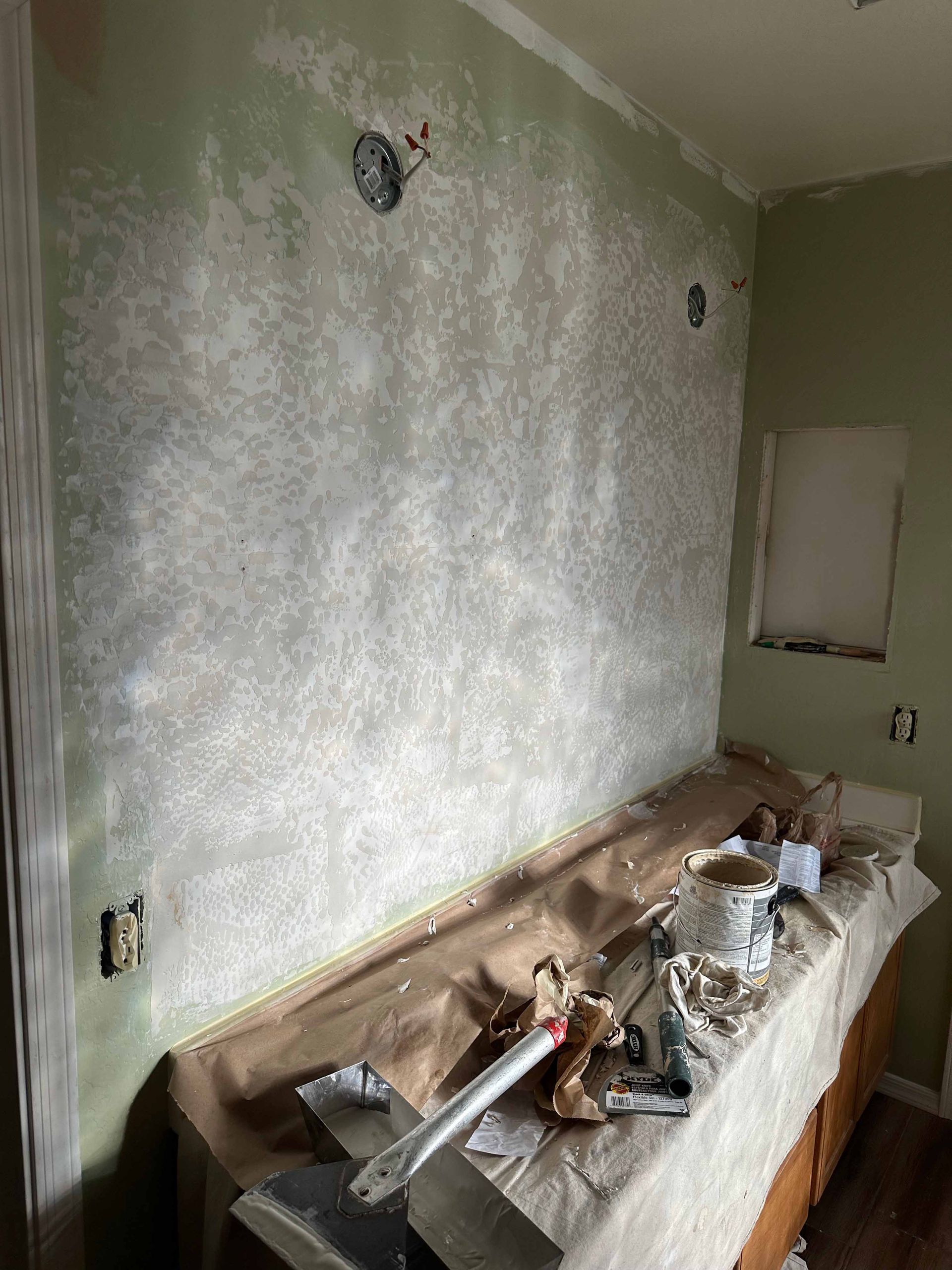 A room with a table and a wall that is being painted.