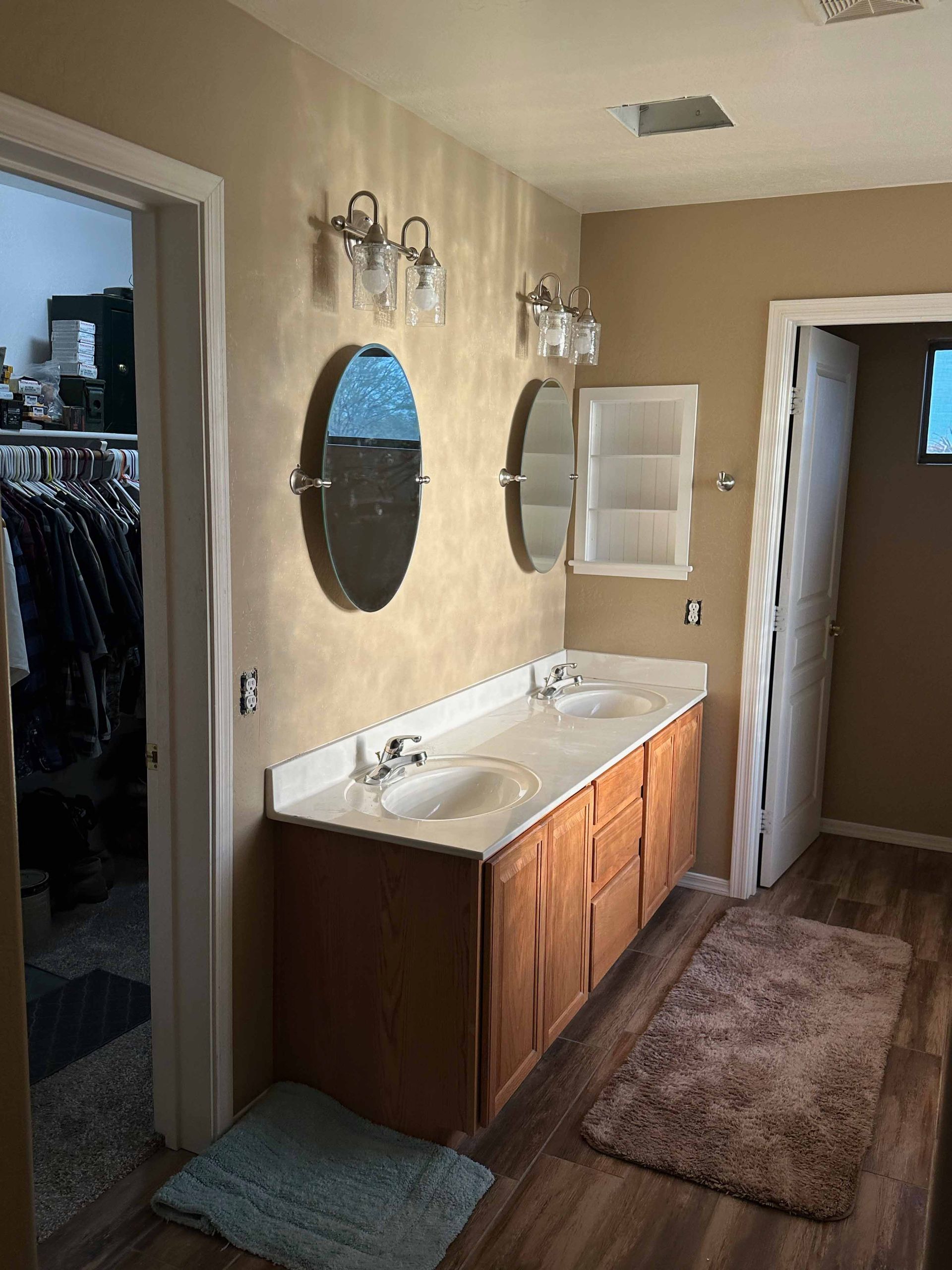 A bathroom with two sinks , two mirrors and a rug.