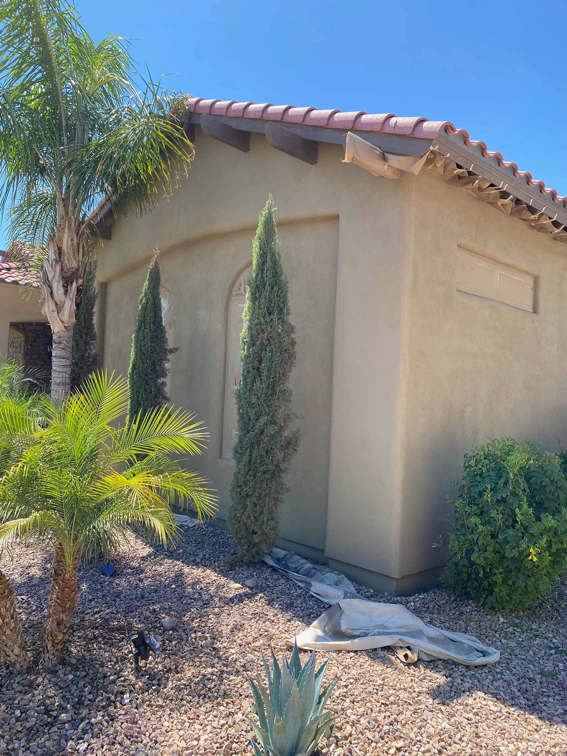 A house with a tiled roof and a few trees in front of it.