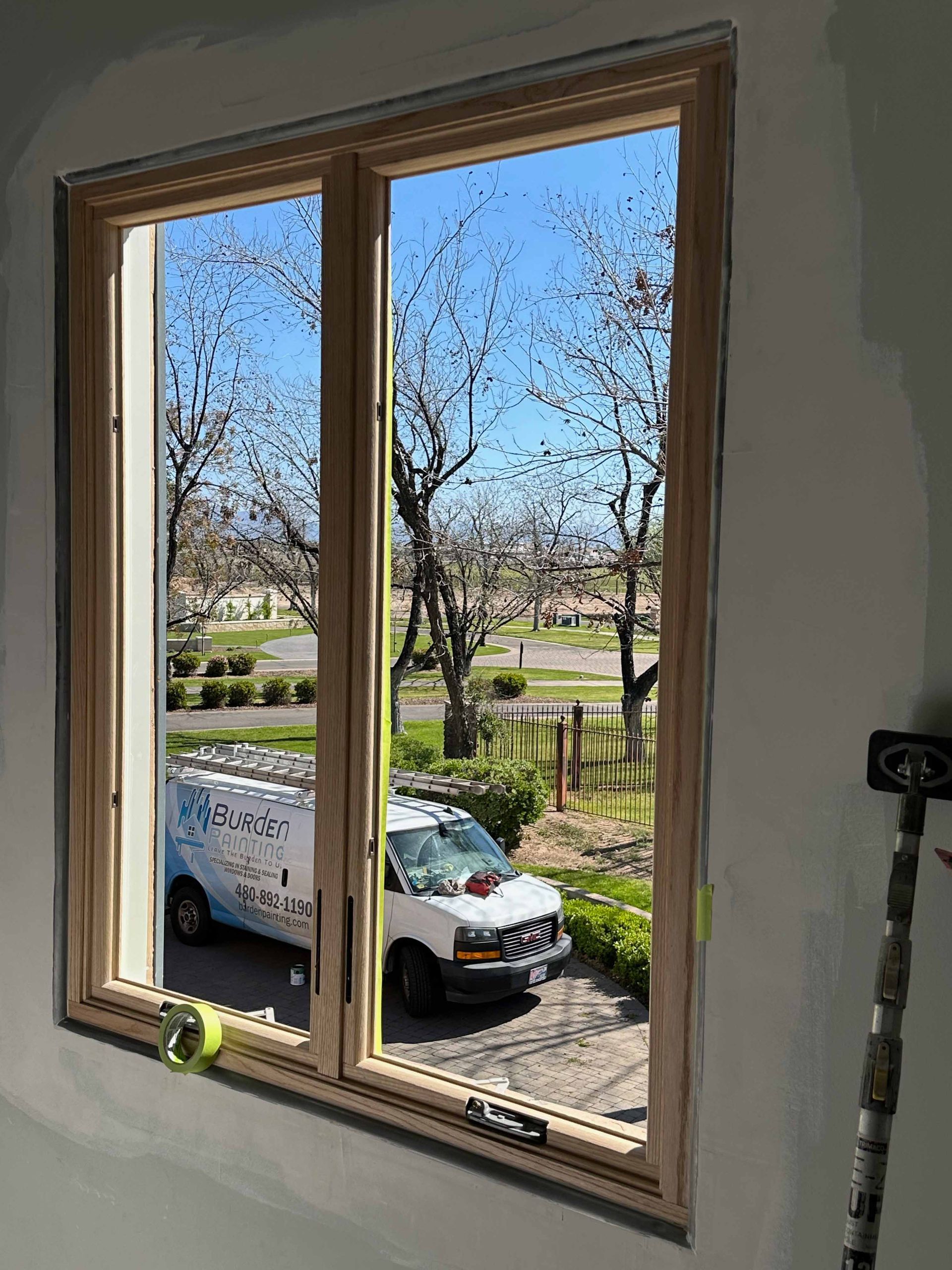 A white van is parked in front of a window.