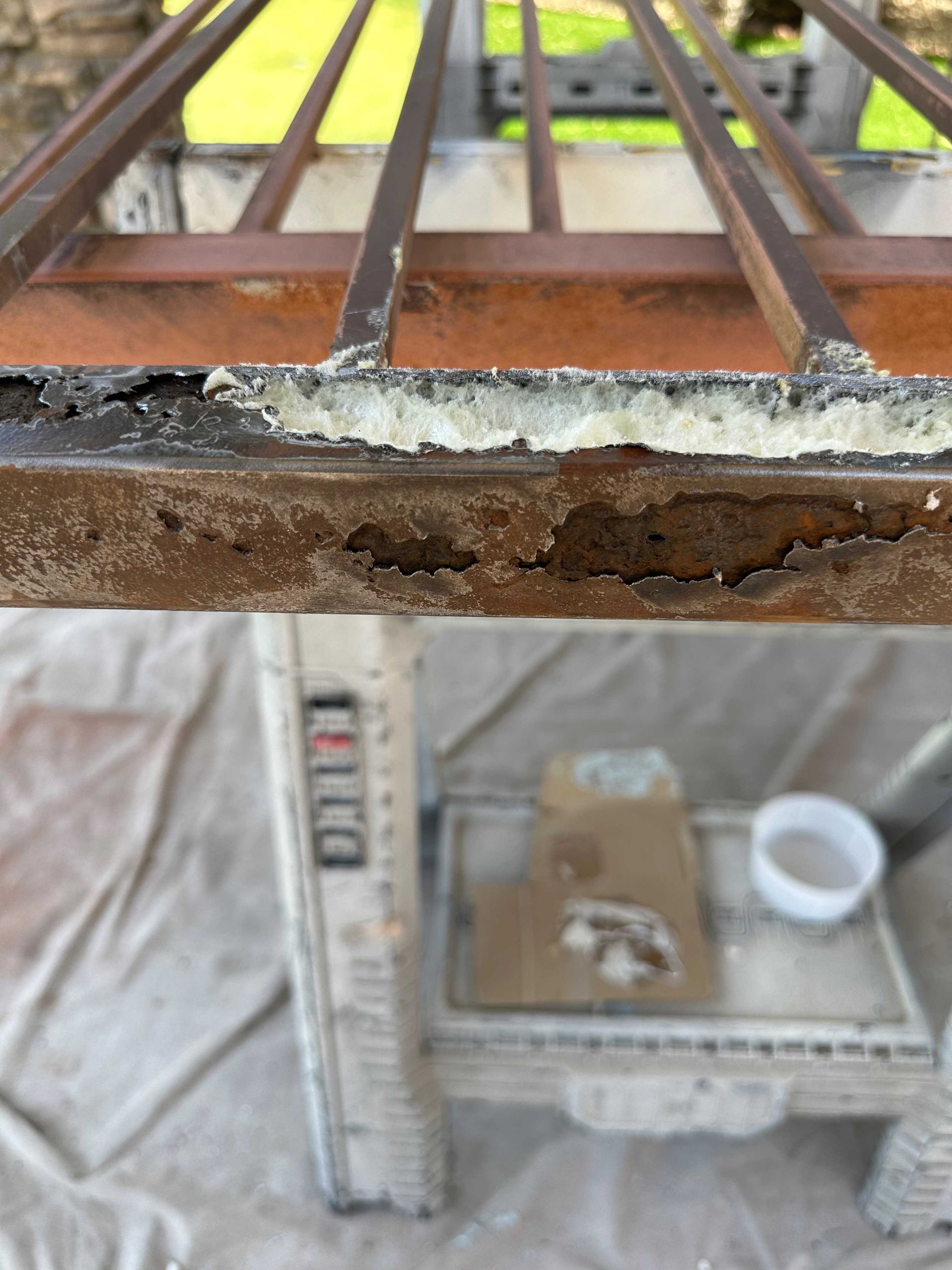 A piece of rusty metal is sitting on a table next to a ladder.