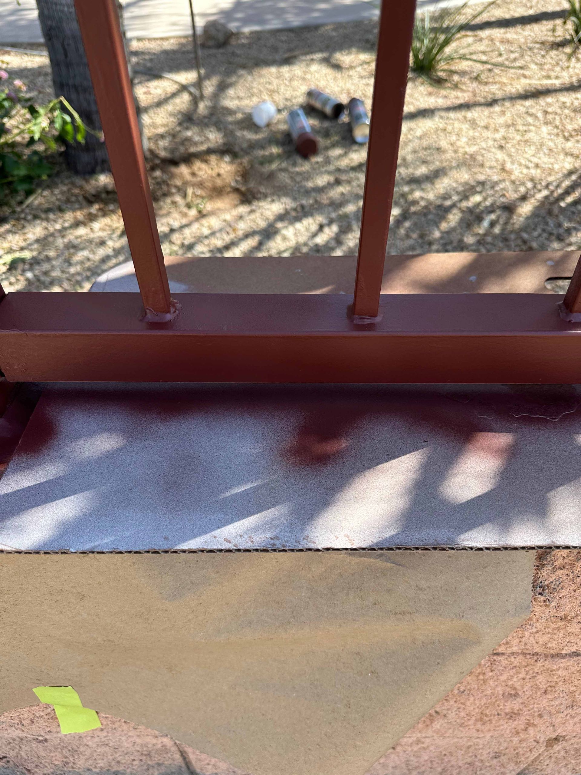A red railing is being painted on a concrete surface.