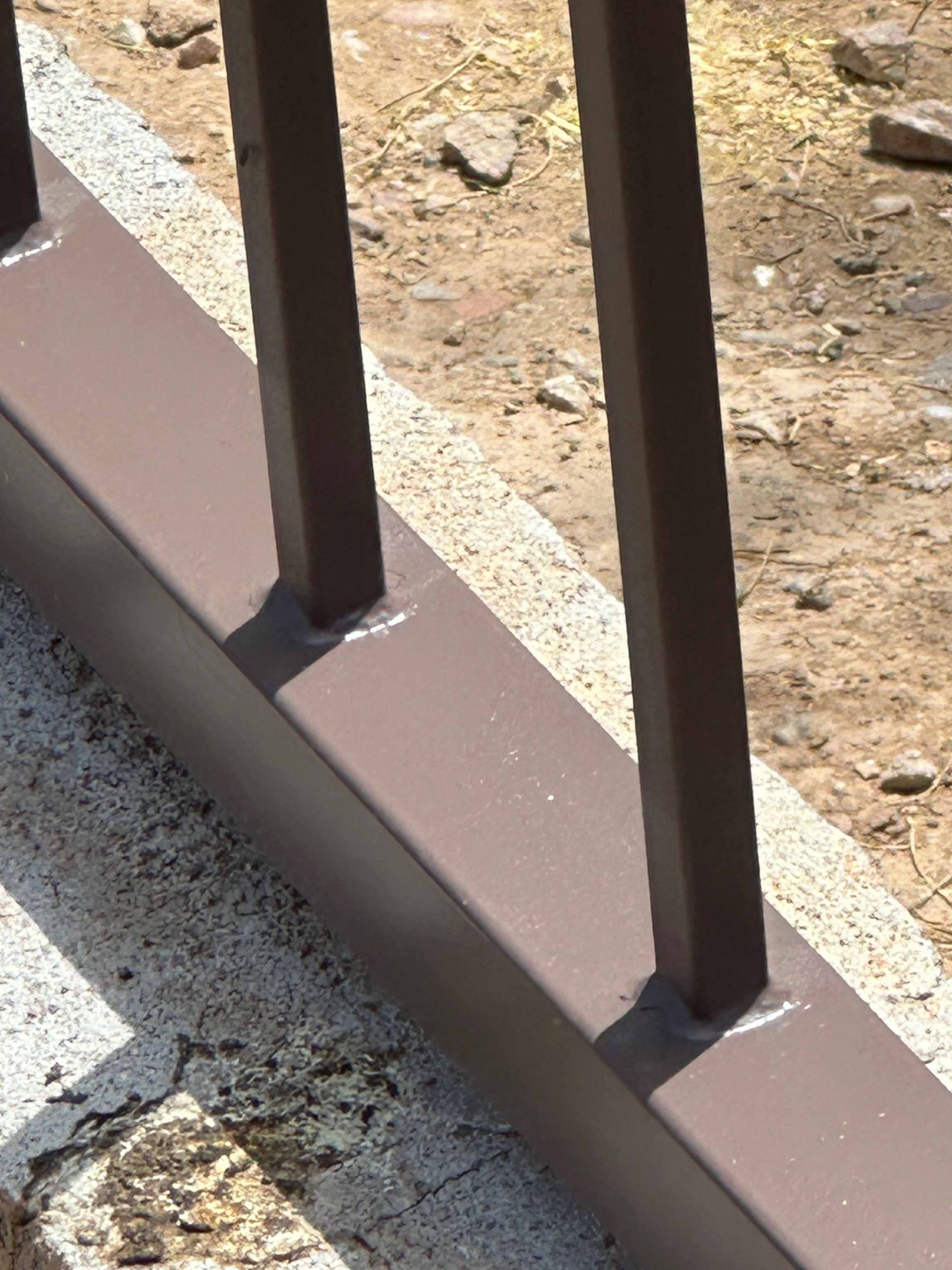 A close up of a brown railing on a concrete surface