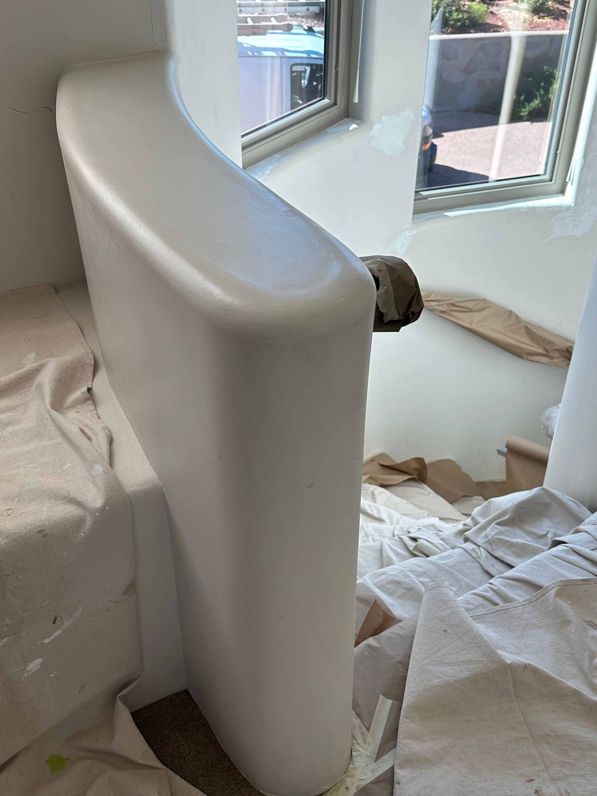 A white toilet is sitting in a room next to a window.