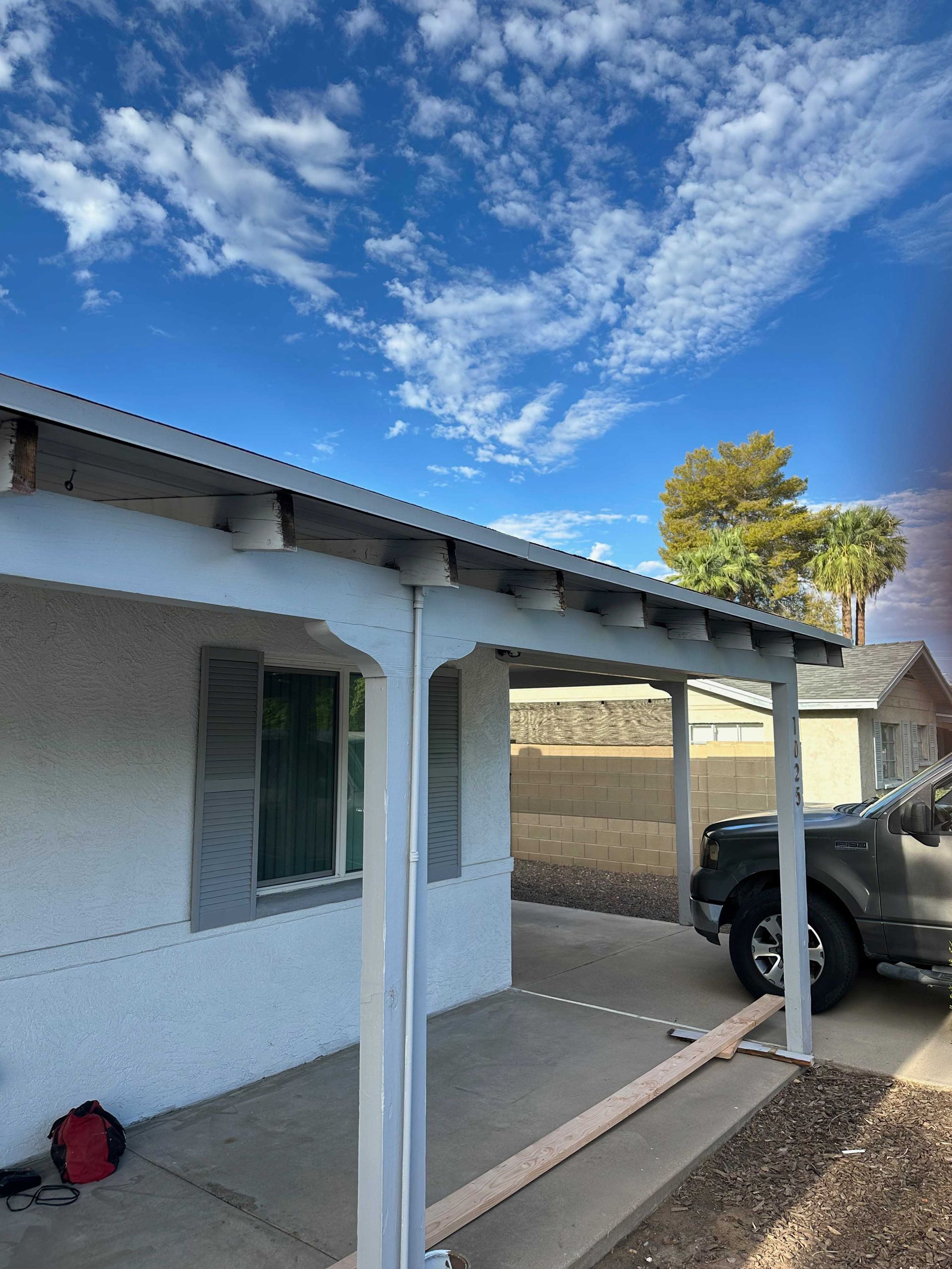 A white house with a covered porch and a truck parked in front of it.