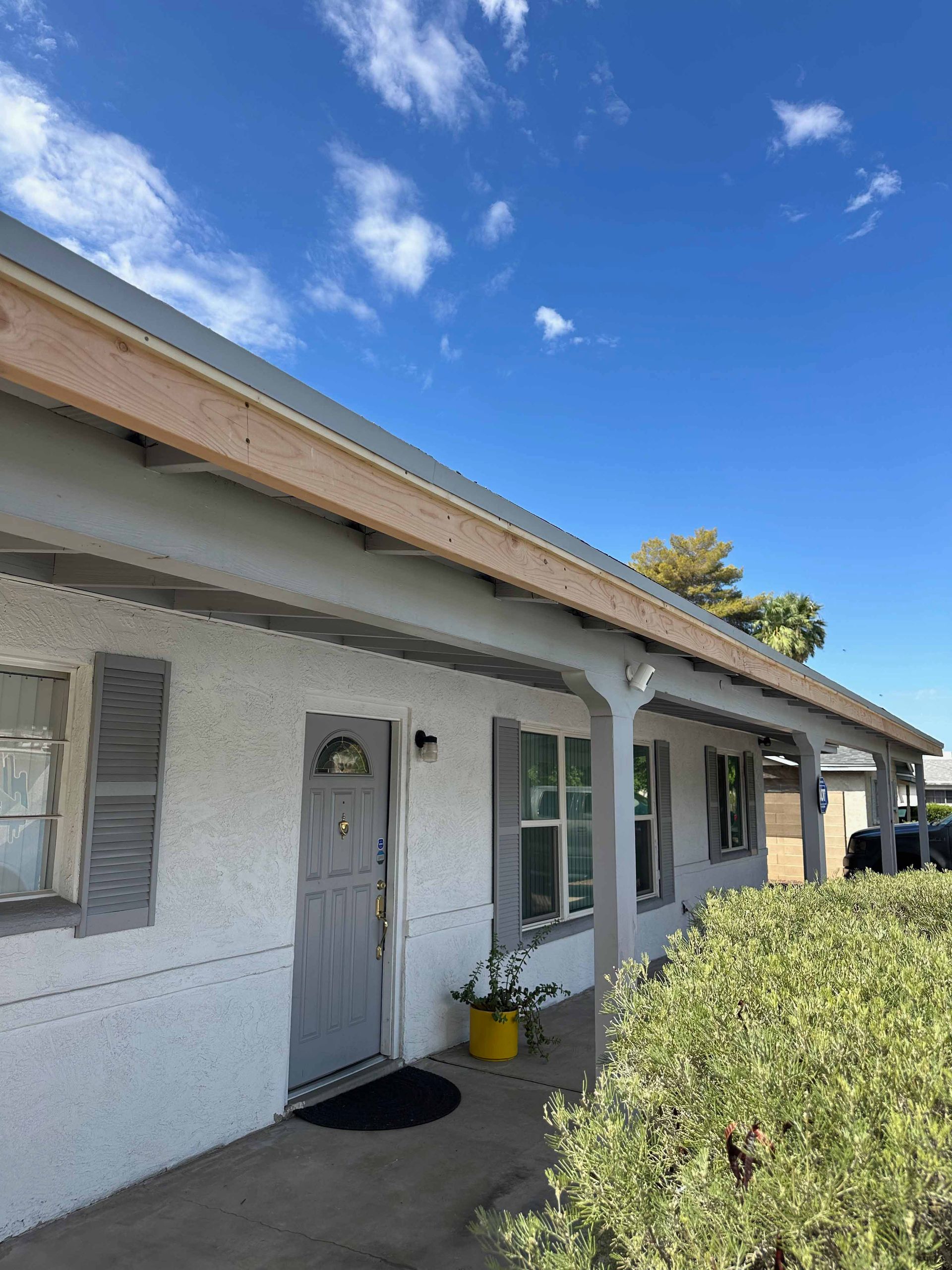 A white house with a porch and a blue sky in the background