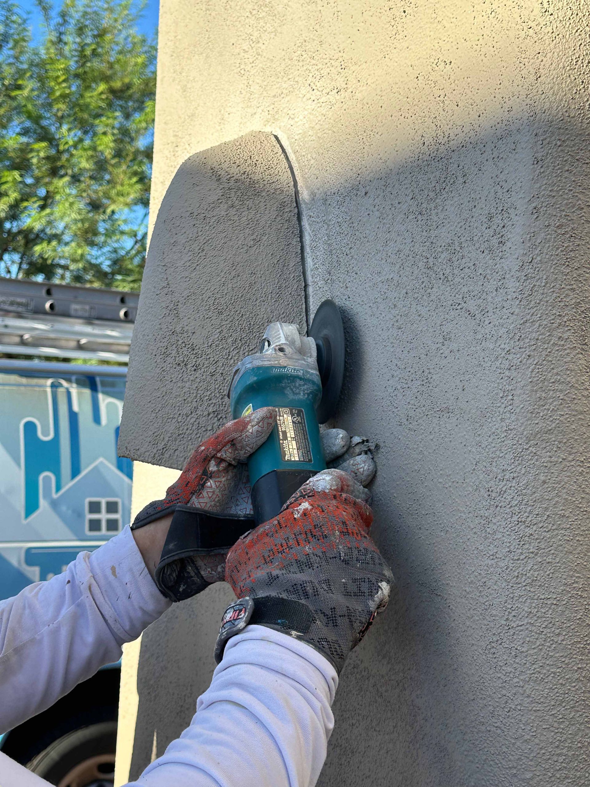 A person is using a grinder on a wall.