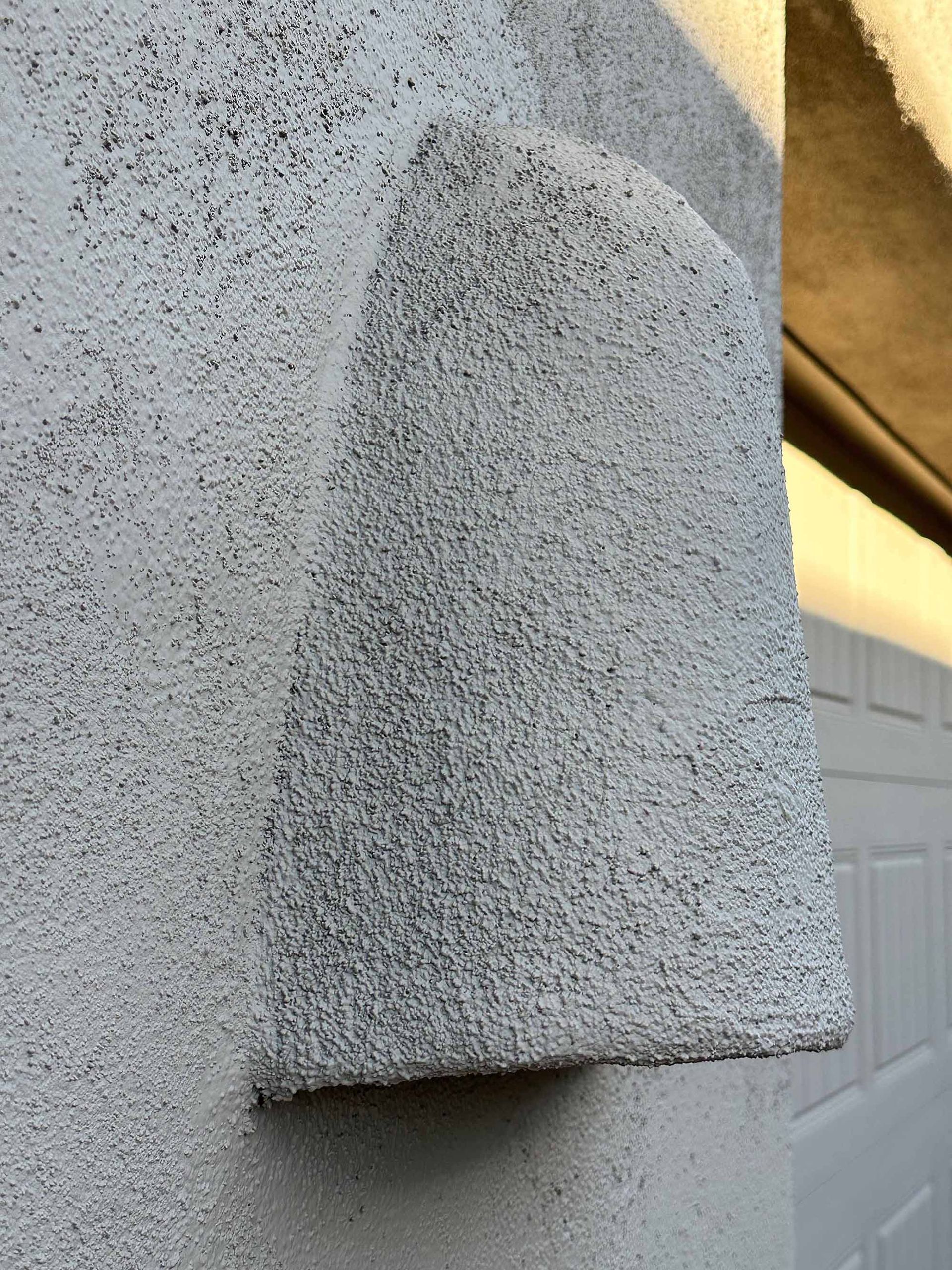 A close up of a white wall with a gray texture.