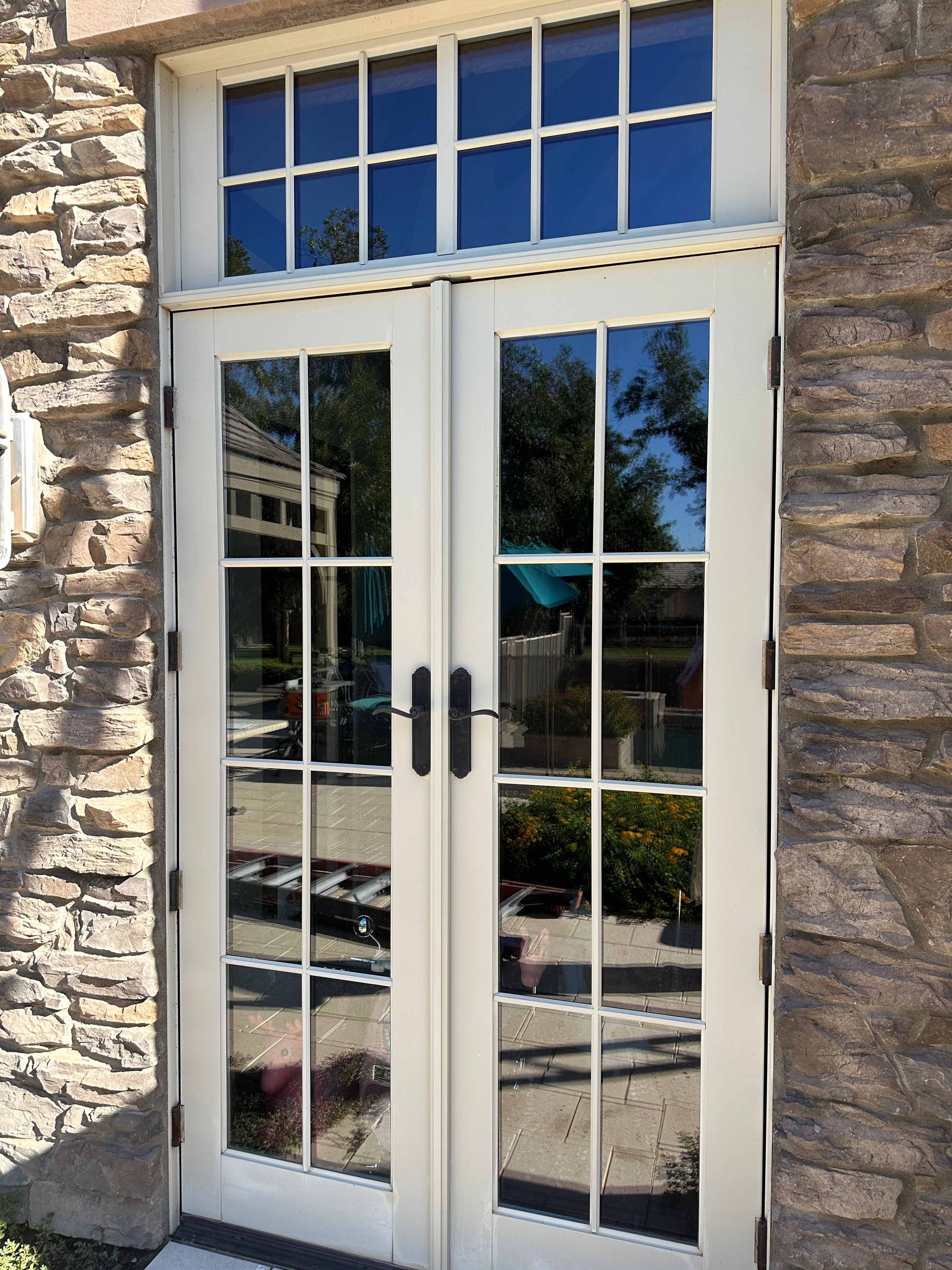 A white french door with a stone wall behind it