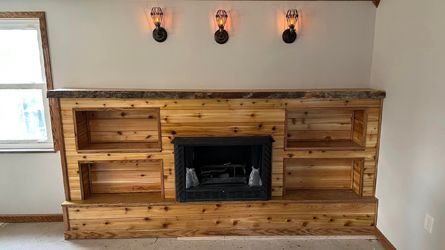 A living room with a wooden fireplace and shelves.