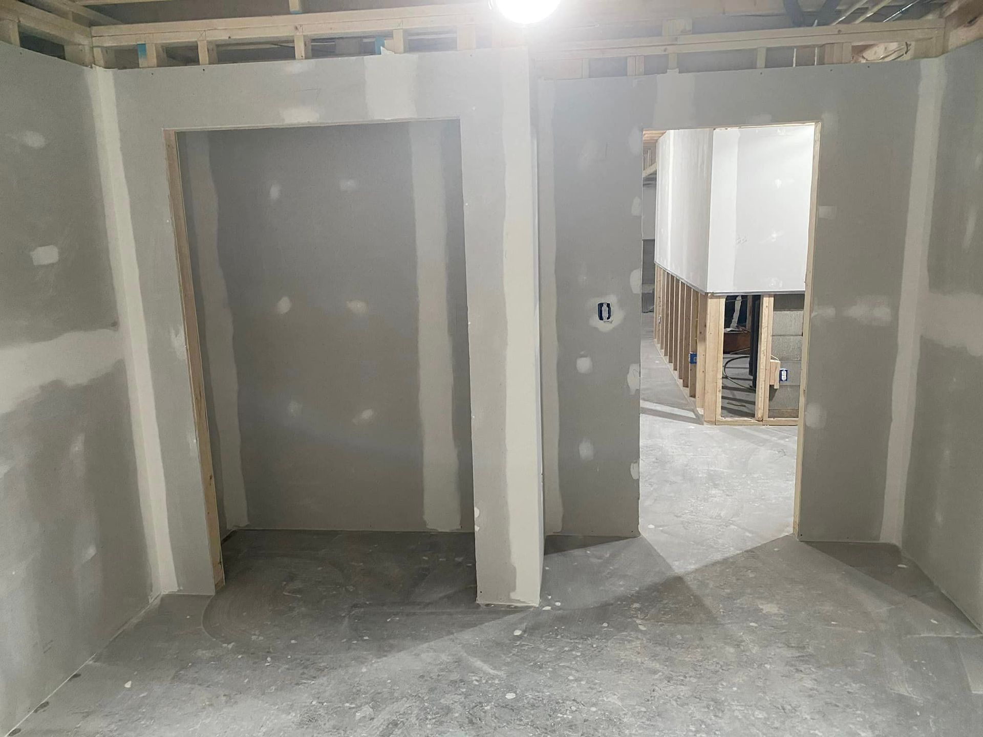 A room with drywall walls and a door in a house under construction.