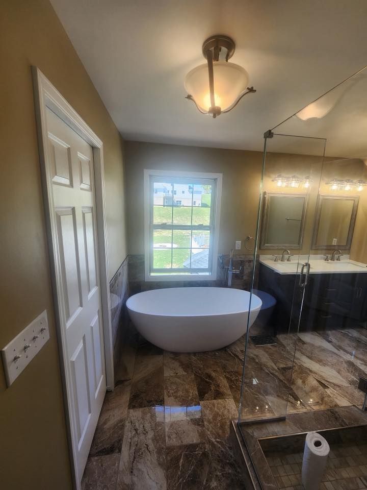 A bathroom with a tub, sink, mirror and window.