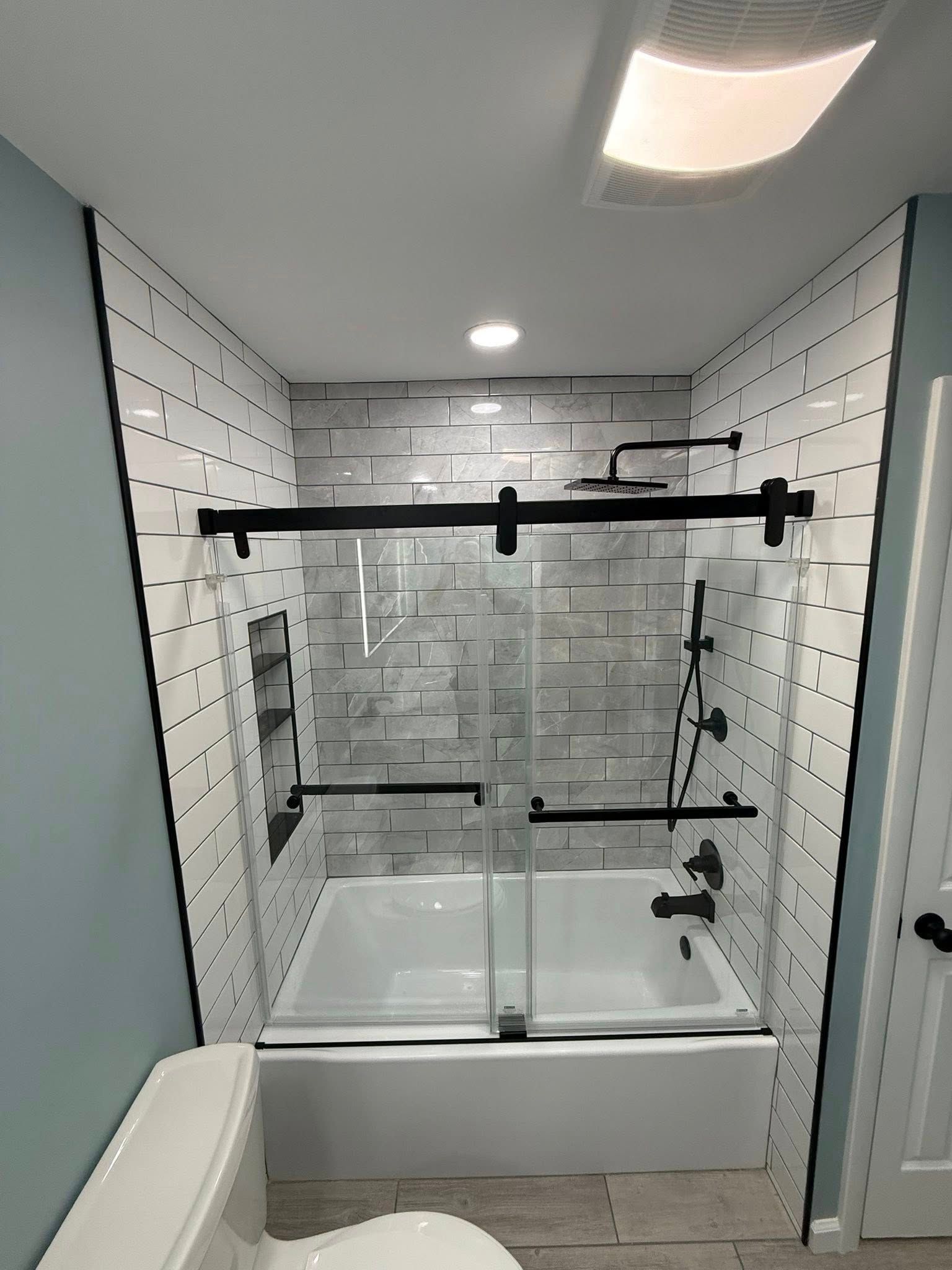 A bathroom with a tub, toilet, shower and sliding glass door.