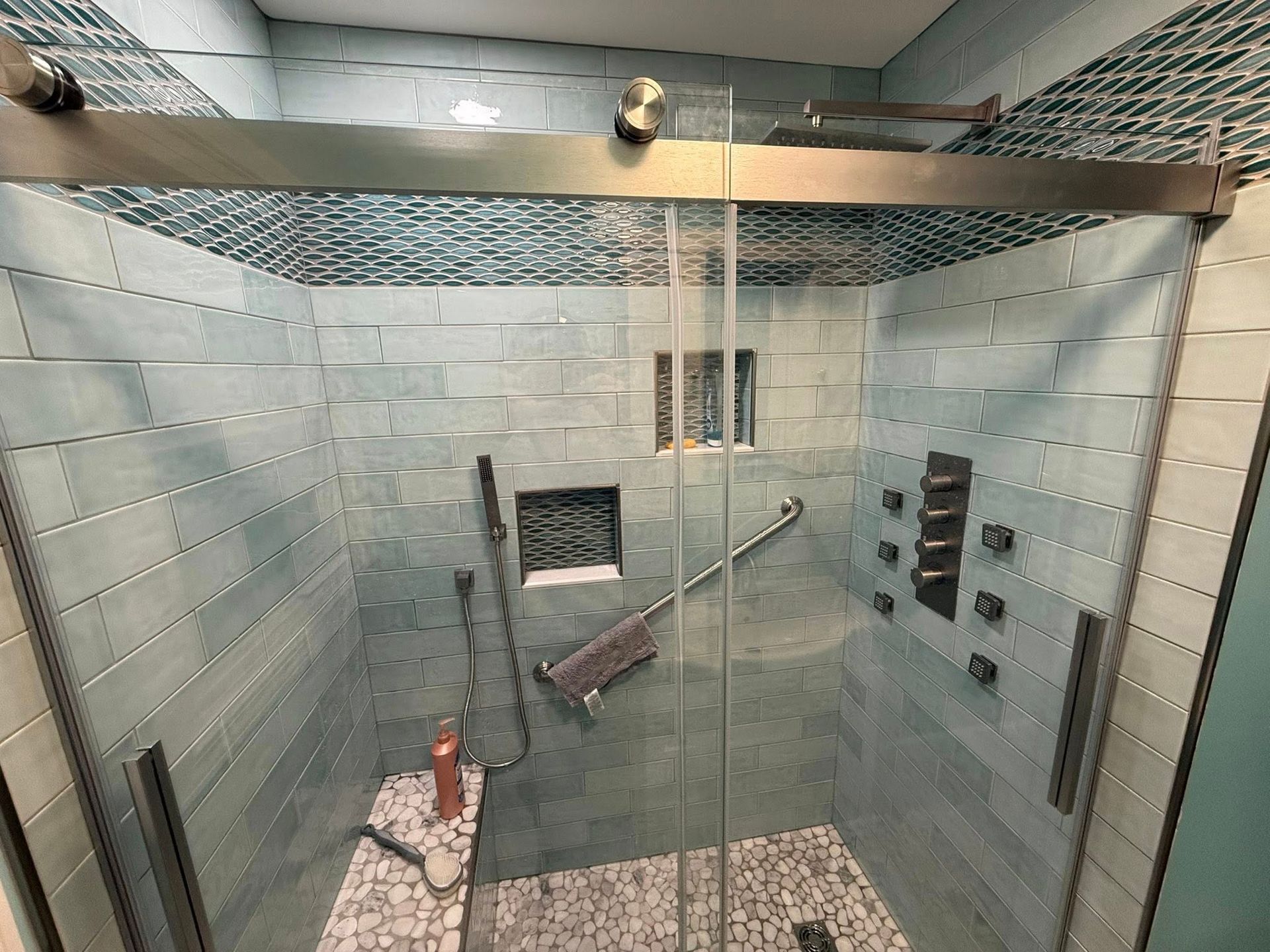 A bathroom with a walk in shower with a sliding glass door.