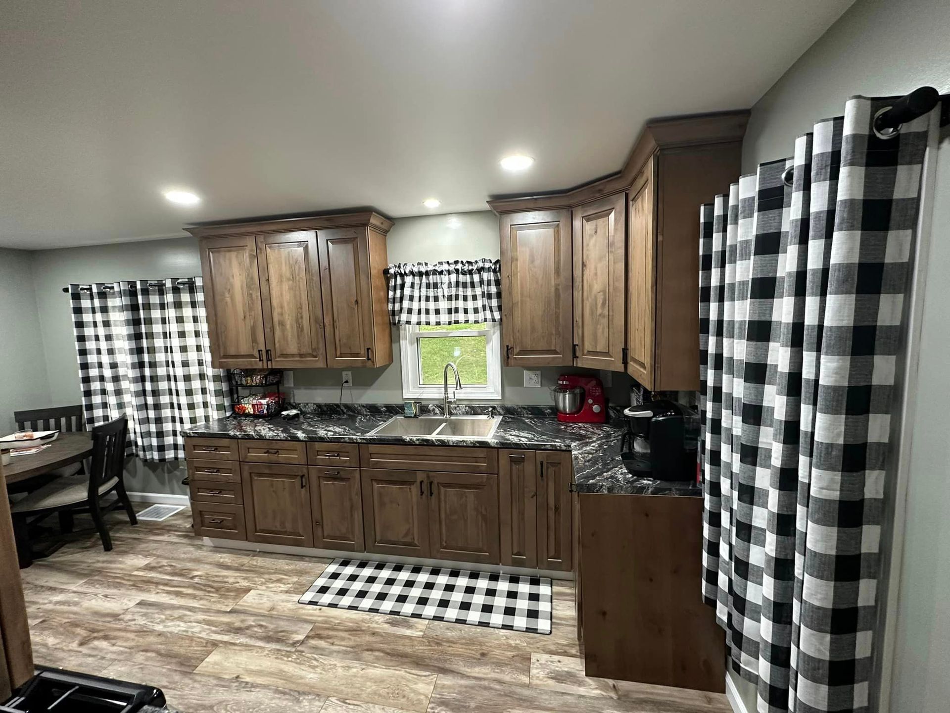 A kitchen with wooden cabinets and black and white checkered curtains.