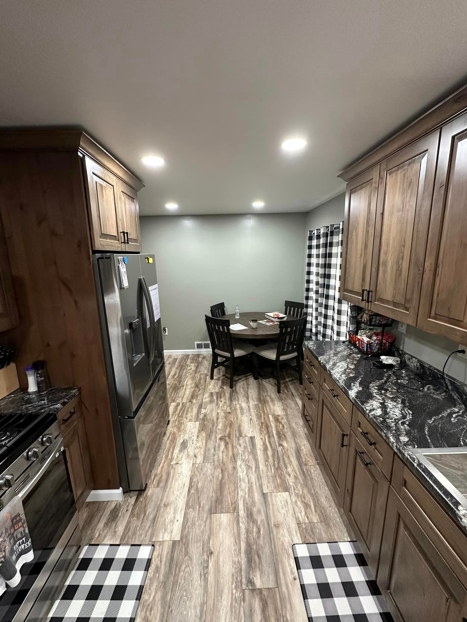 A kitchen with wooden cabinets , granite counter tops , a refrigerator , a table and chairs.