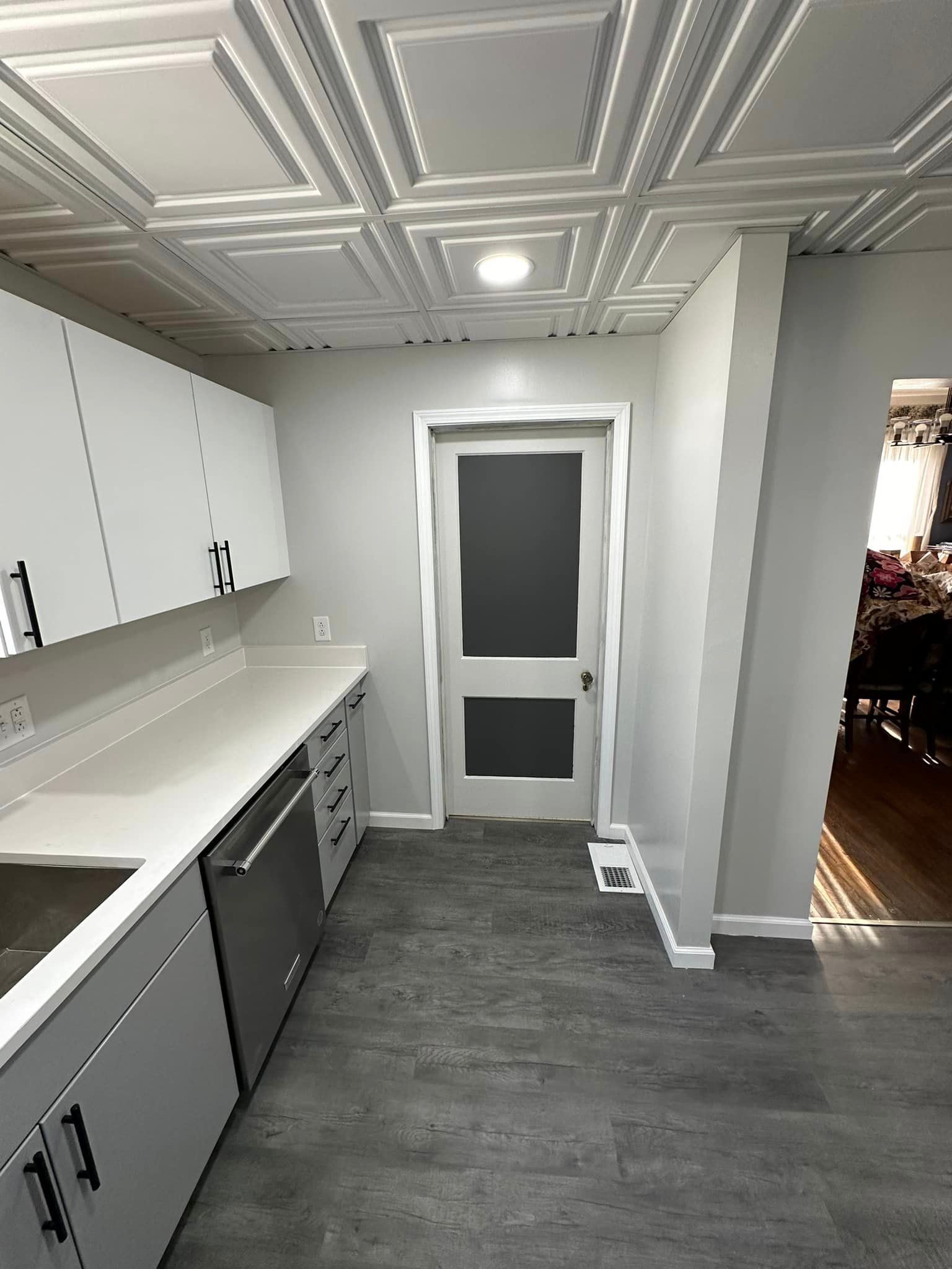 A kitchen with white cabinets , a sink , and a door.