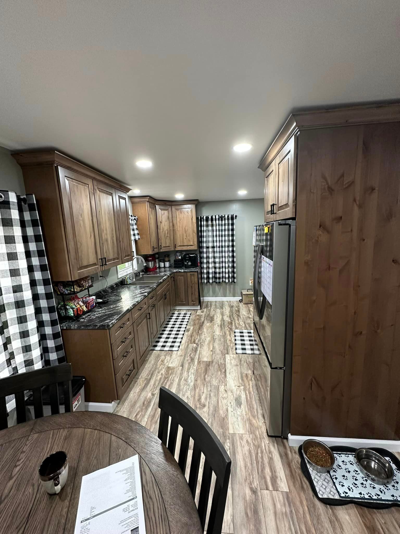 A kitchen with wooden cabinets , stainless steel appliances , a table and chairs.