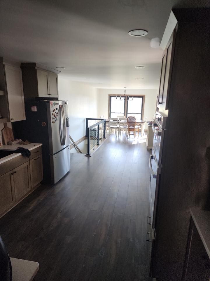 A kitchen with a refrigerator and a dining room in the background.