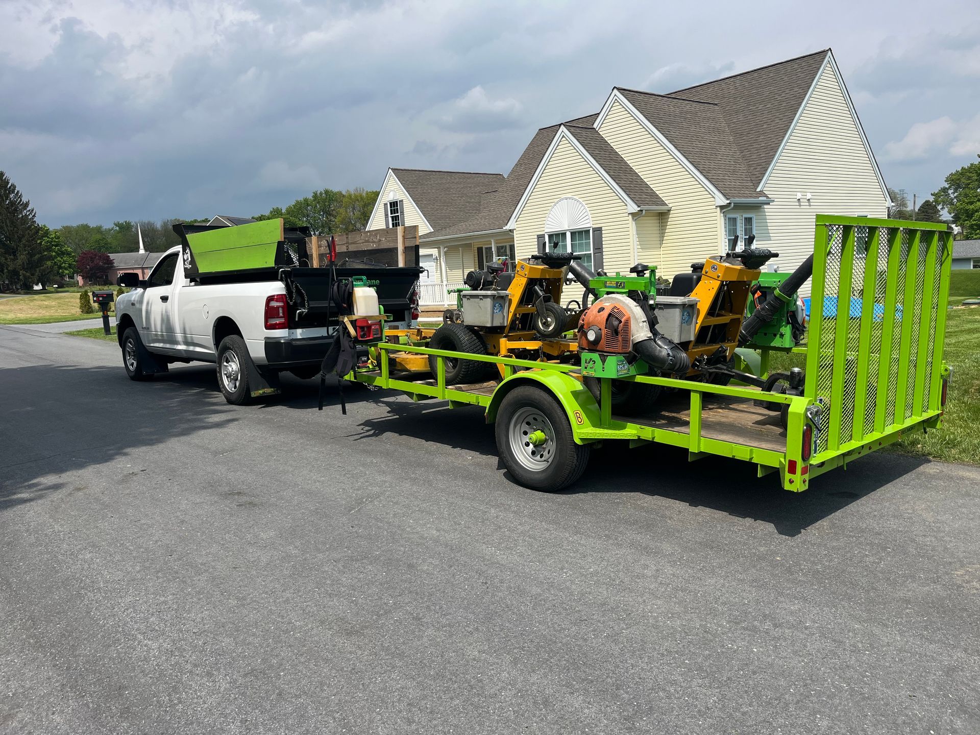 a white truck is towing a green trailer with a tractor on it