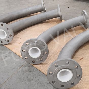 Curved pipes with white ceramic lining and flanged ends, lying on a wooden surface.