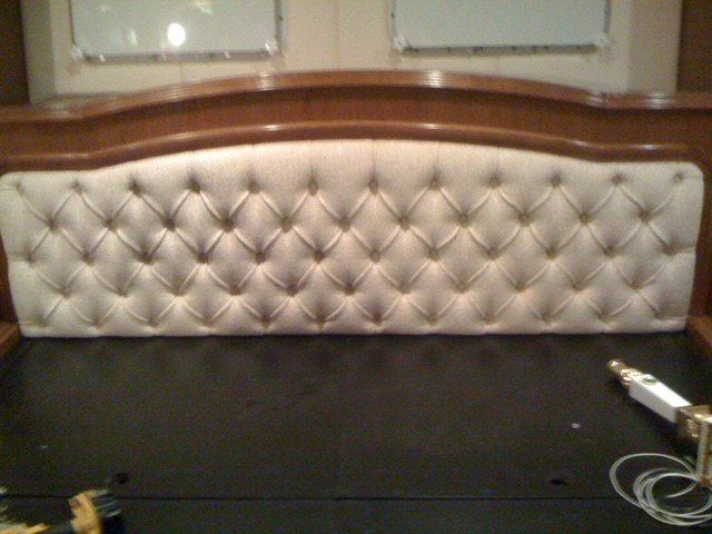 A bed with a tufted headboard and a remote control