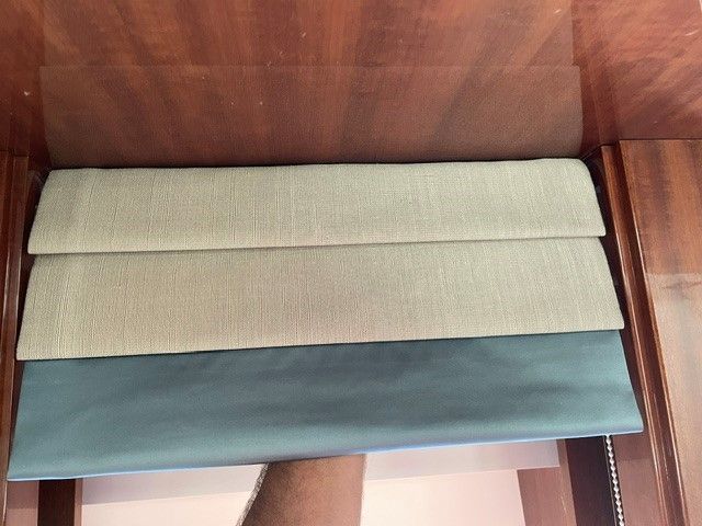 A person is holding a piece of fabric on top of a wooden table.