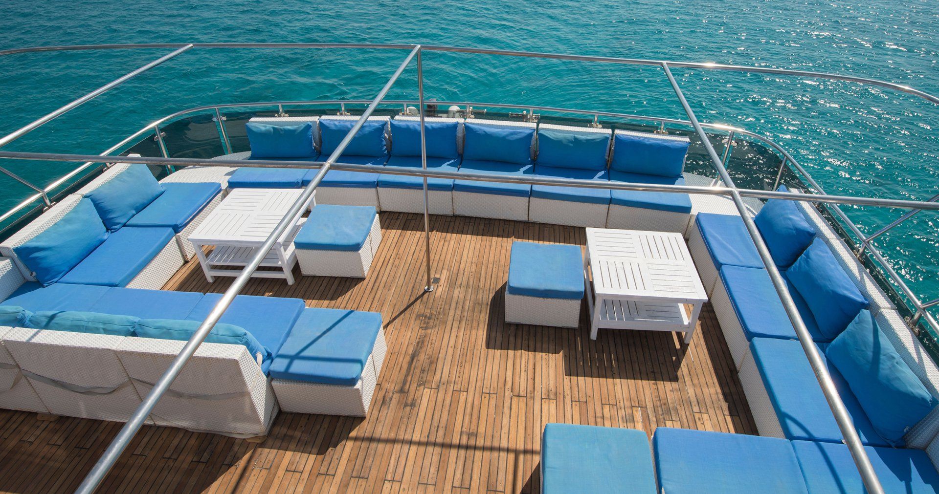 the deck of a boat with blue and white furniture and a table