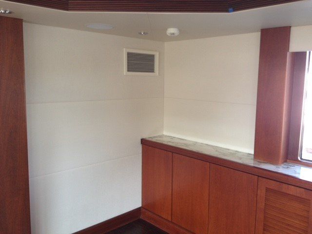 A corner of a room with white walls and wooden cabinets