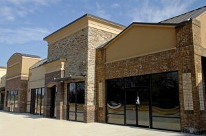 Empty retail storefronts with brick and tan exteriors, under a blue sky.