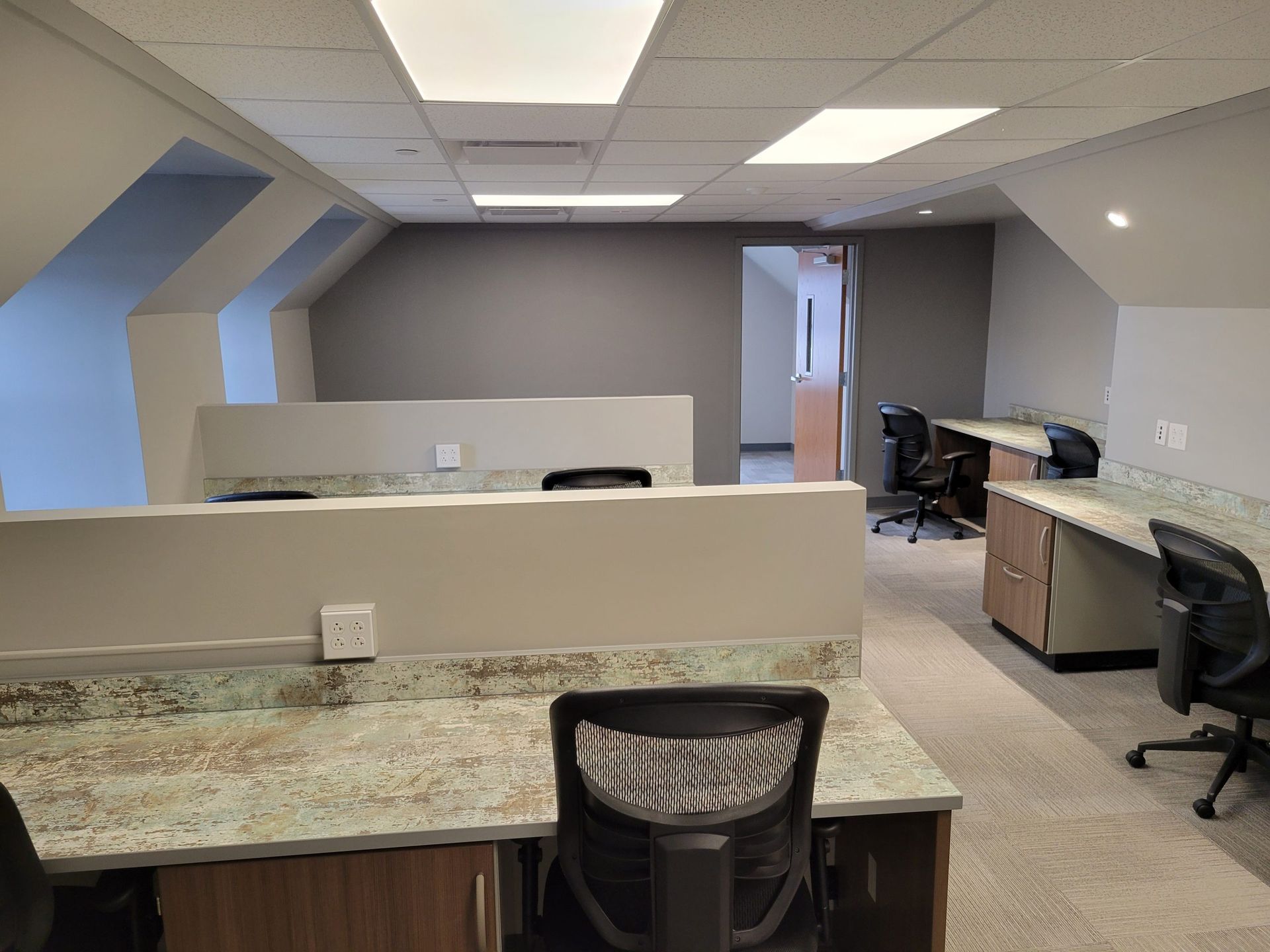 Office space with workstations, beige walls, and overhead lighting.