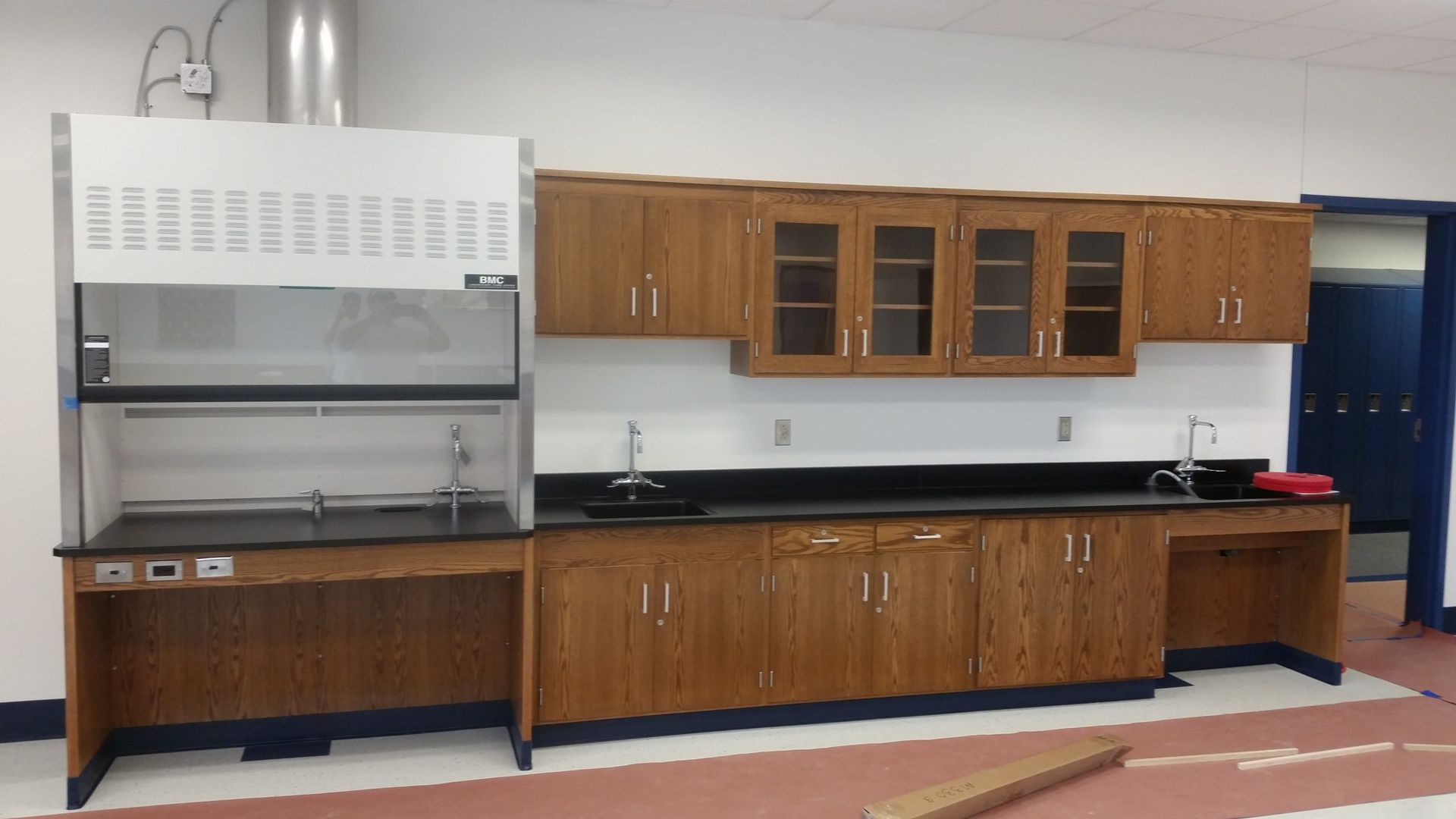 Laboratory with wood cabinets, black countertops, and a fume hood.