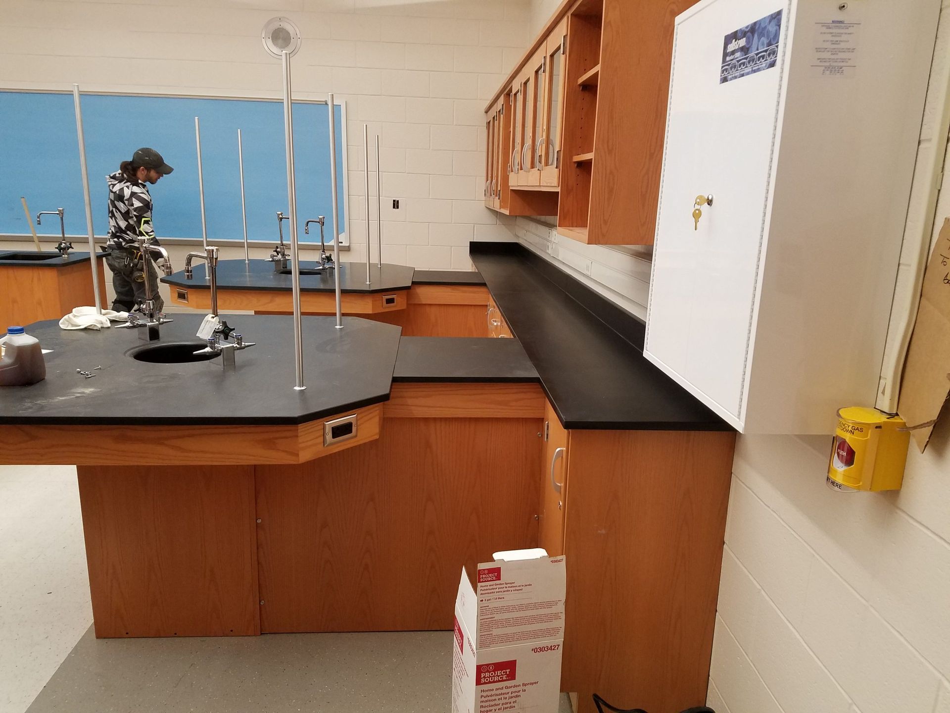 Science lab with wooden cabinetry, black countertops, and a person working.