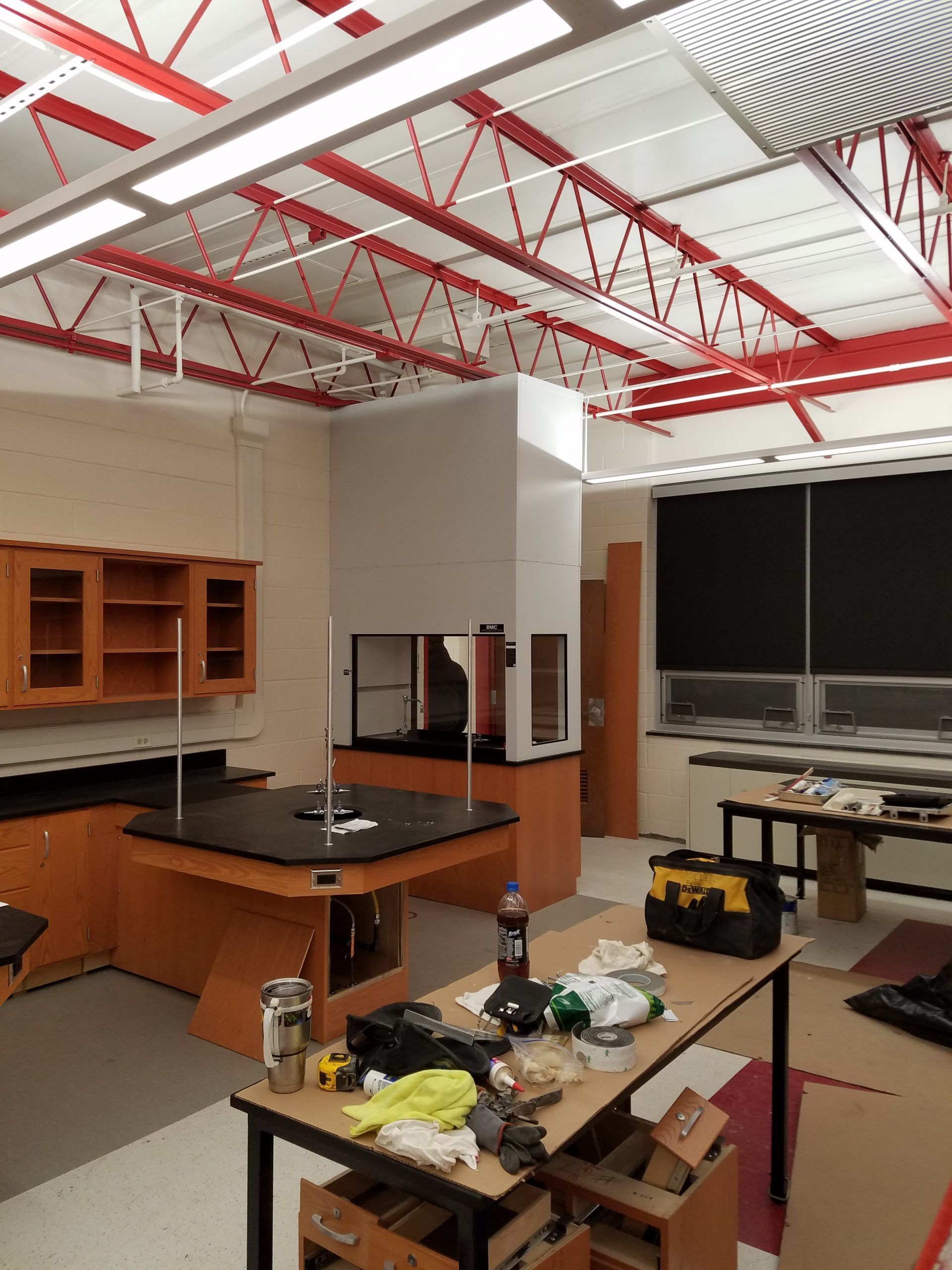 Laboratory interior with lab benches, a fume hood, and exposed red ceiling beams.