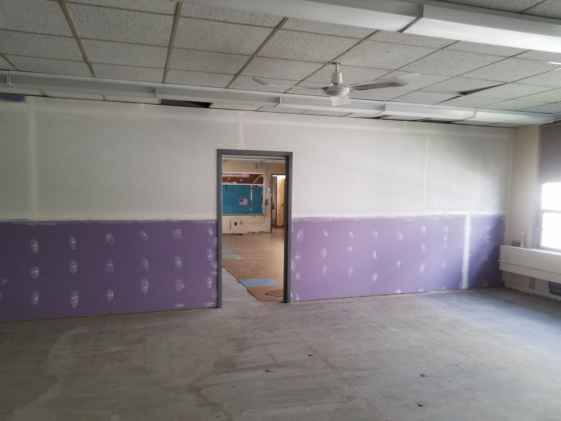 Empty room under construction with purple drywall and an open doorway.